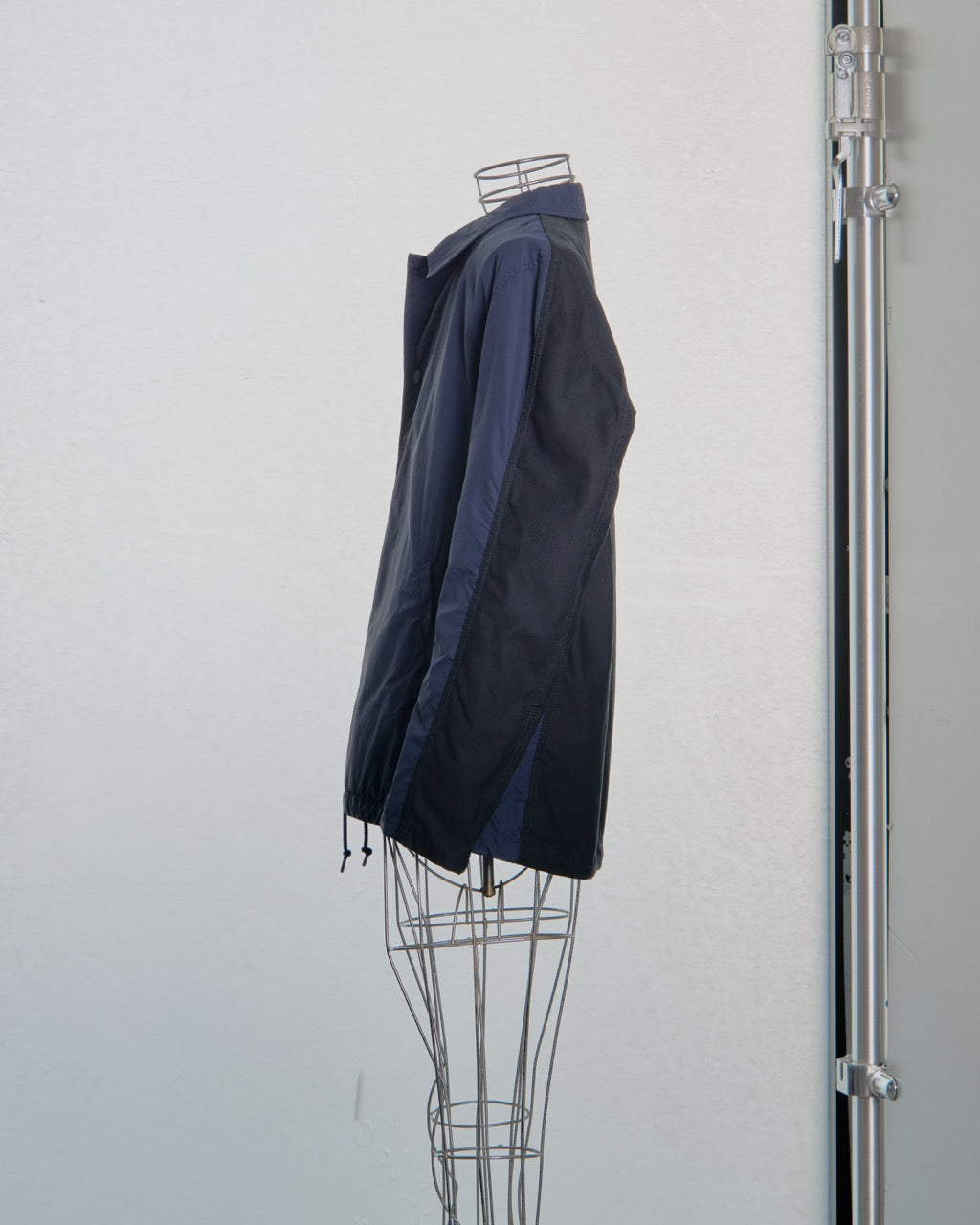 Navy blue and black Comme des Garcons jacket on a mannequin against a white background