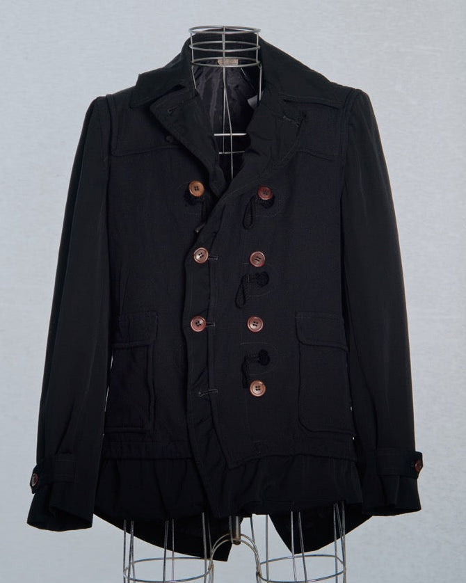 Black Comme des Garcons peacoat with brown buttons on a mannequin against a light gray background