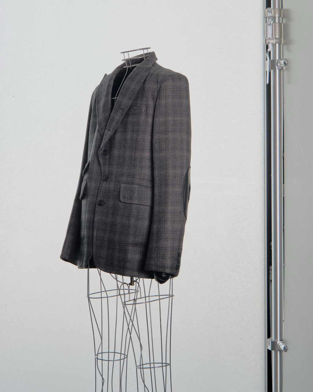 Gray checkered Comme des Garcons Junya Watanabe blazer on a mannequin against a white background