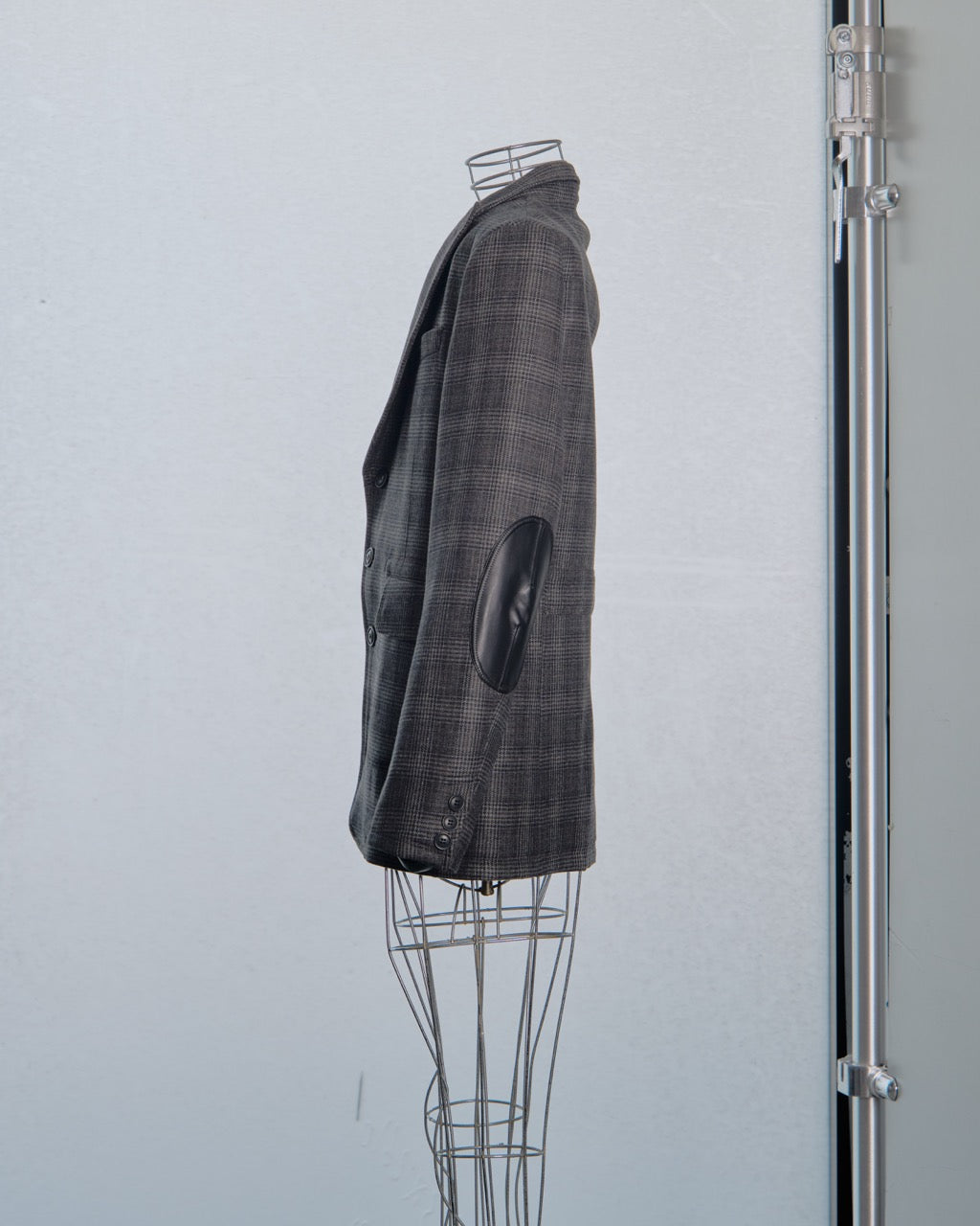 Gray checkered Comme des Garcons Junya Watanabe coat on a mannequin against a light gray background