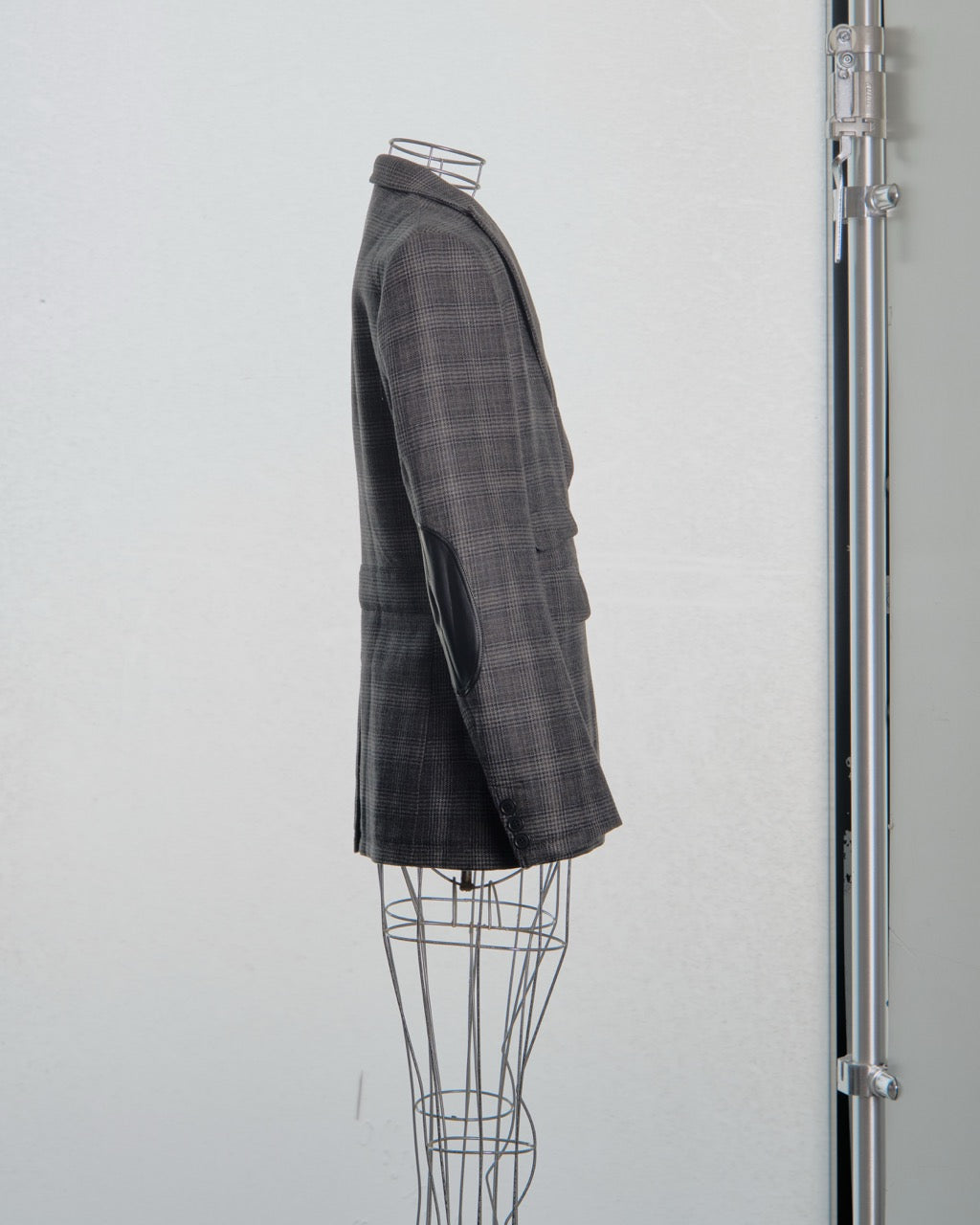 Gray checkered Comme des Garcons Junya Watanabe  blazer on a mannequin against a white background