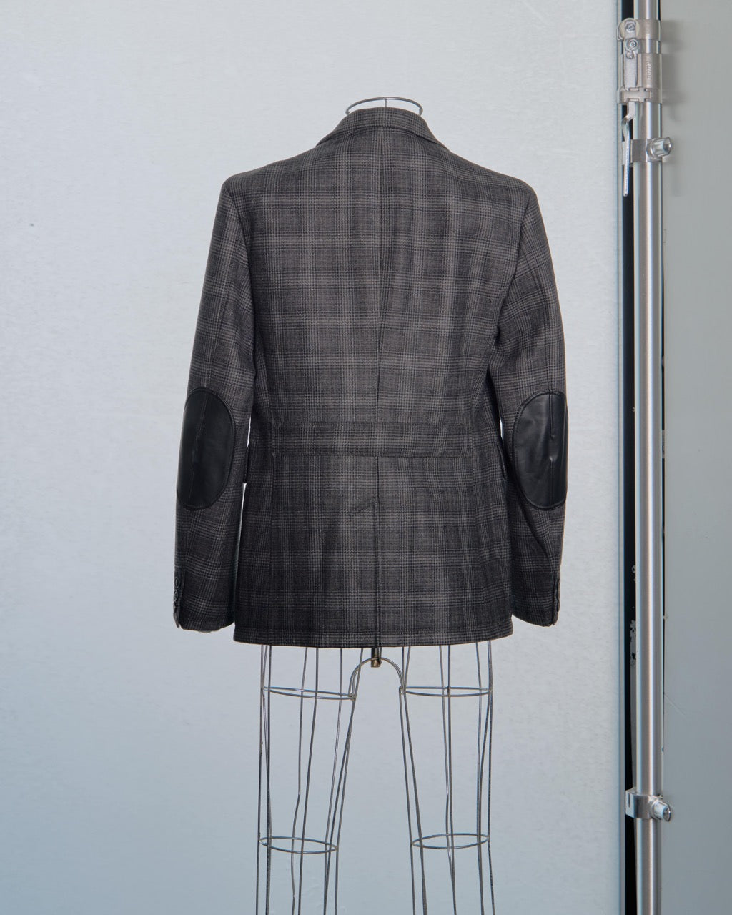 Gray checkered Comme des Garcons Junya Watanabe blazer on a mannequin against a light gray background