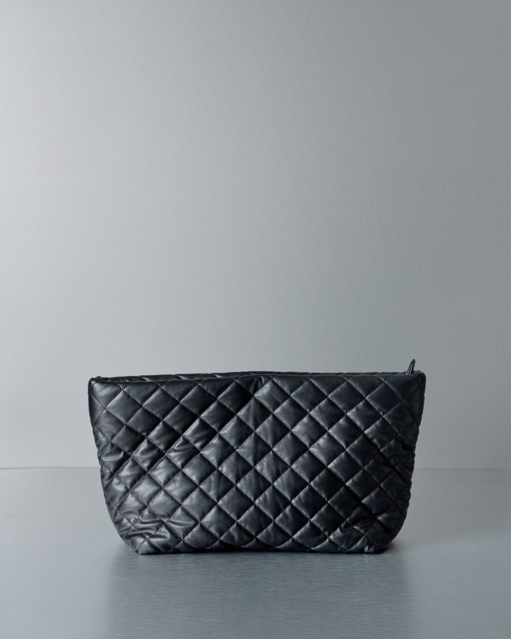 Black quilted Comme des Garcons Junya Watanabe  handbag on a gray background