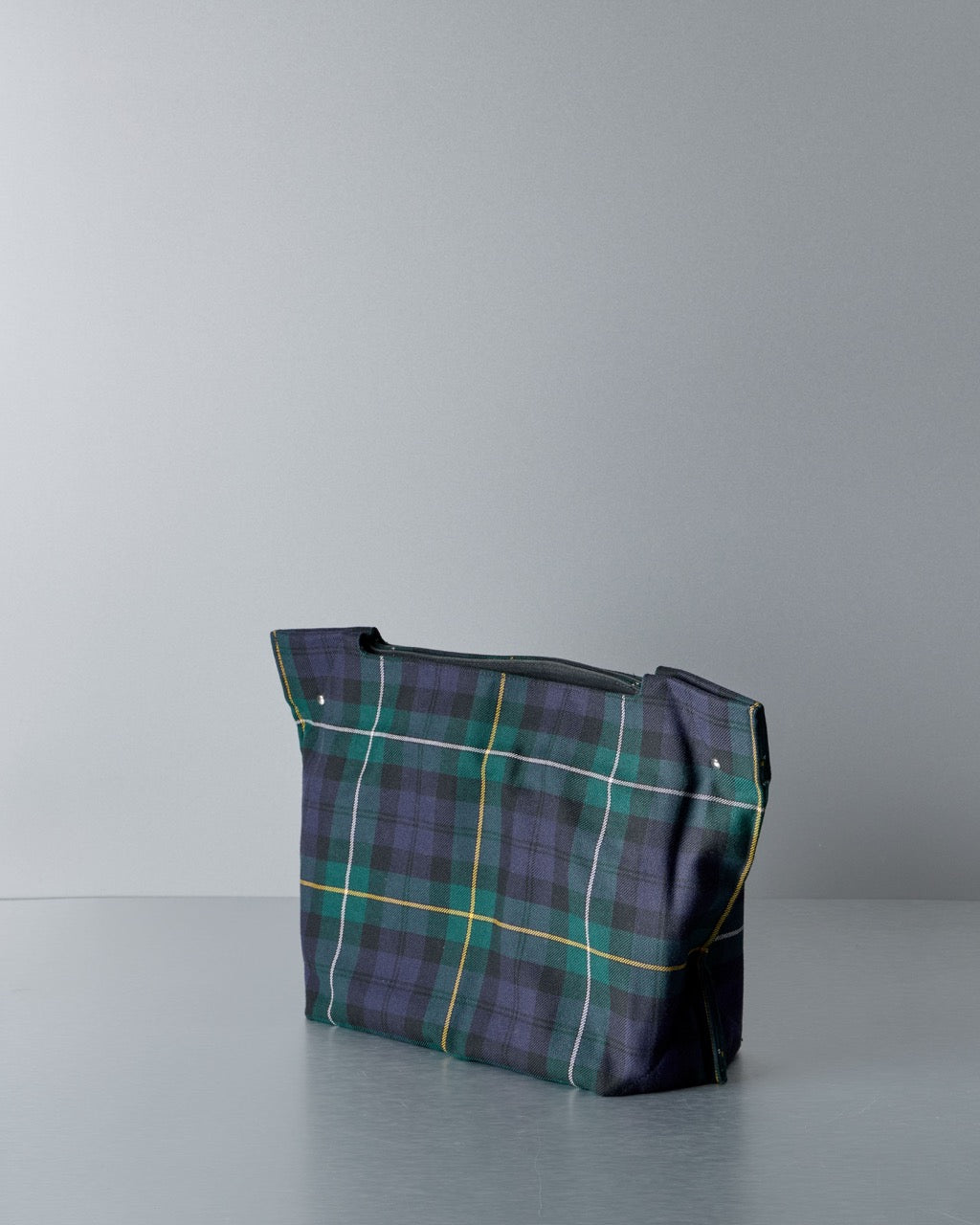 Plaid Comme des Garcons  tote bag on a gray surface with a light gray background