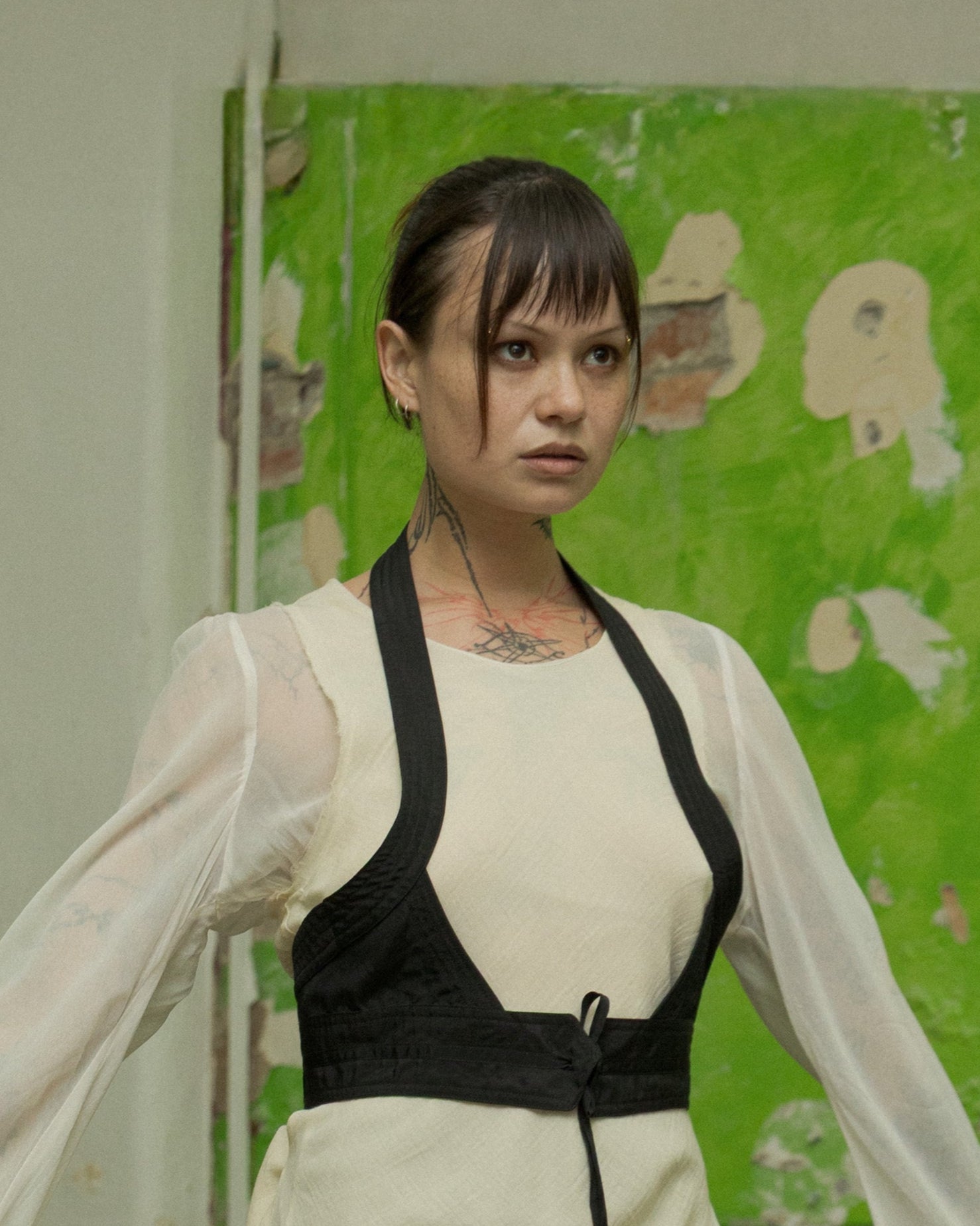 Person in a white Comme Des Garcons outfit with black accents standing in an abandoned interior setting.