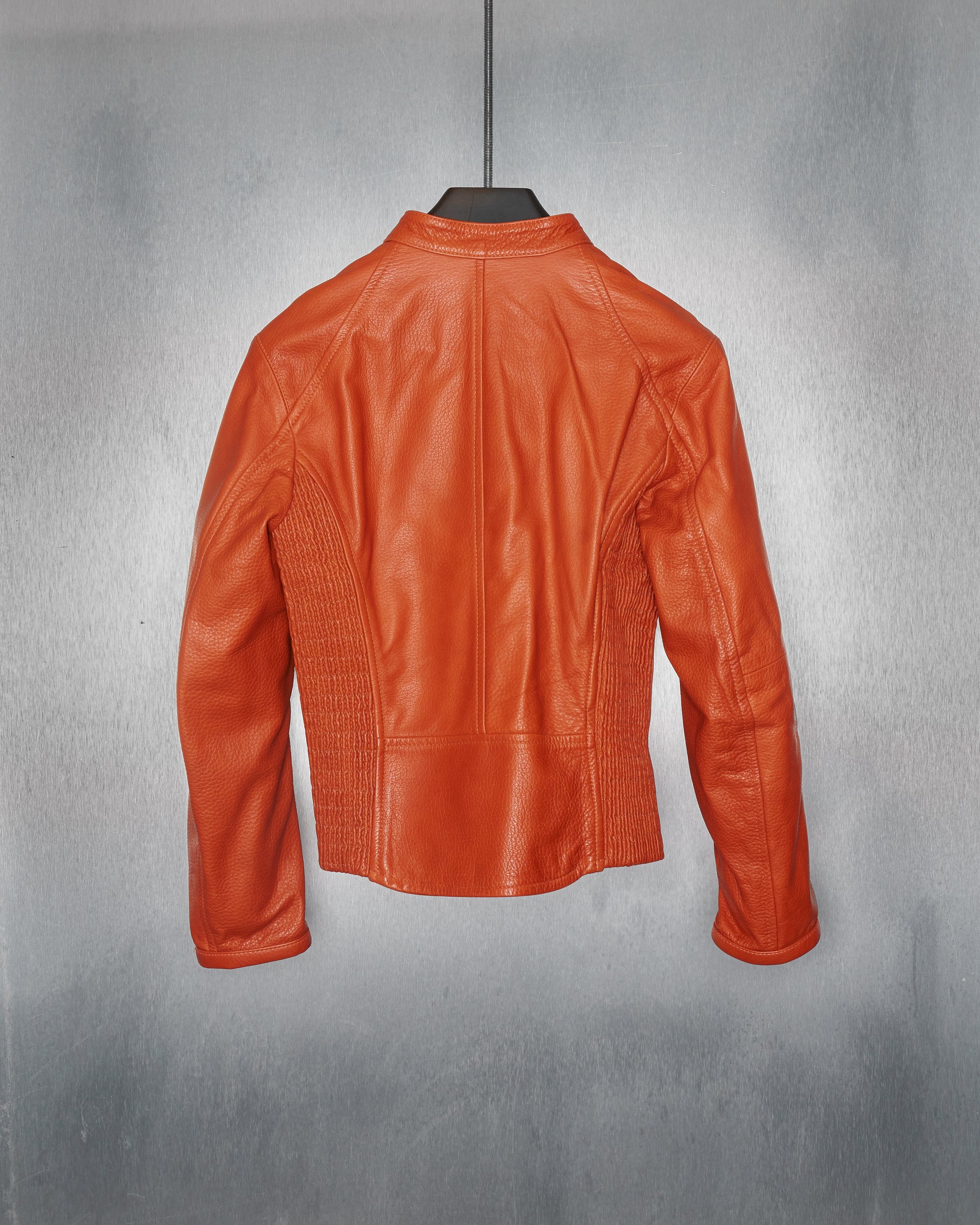 Back view of an orange leather DSquared2 jacket on a hanger against a metallic textured background. The jacket has a fitted style with detailed stitching.