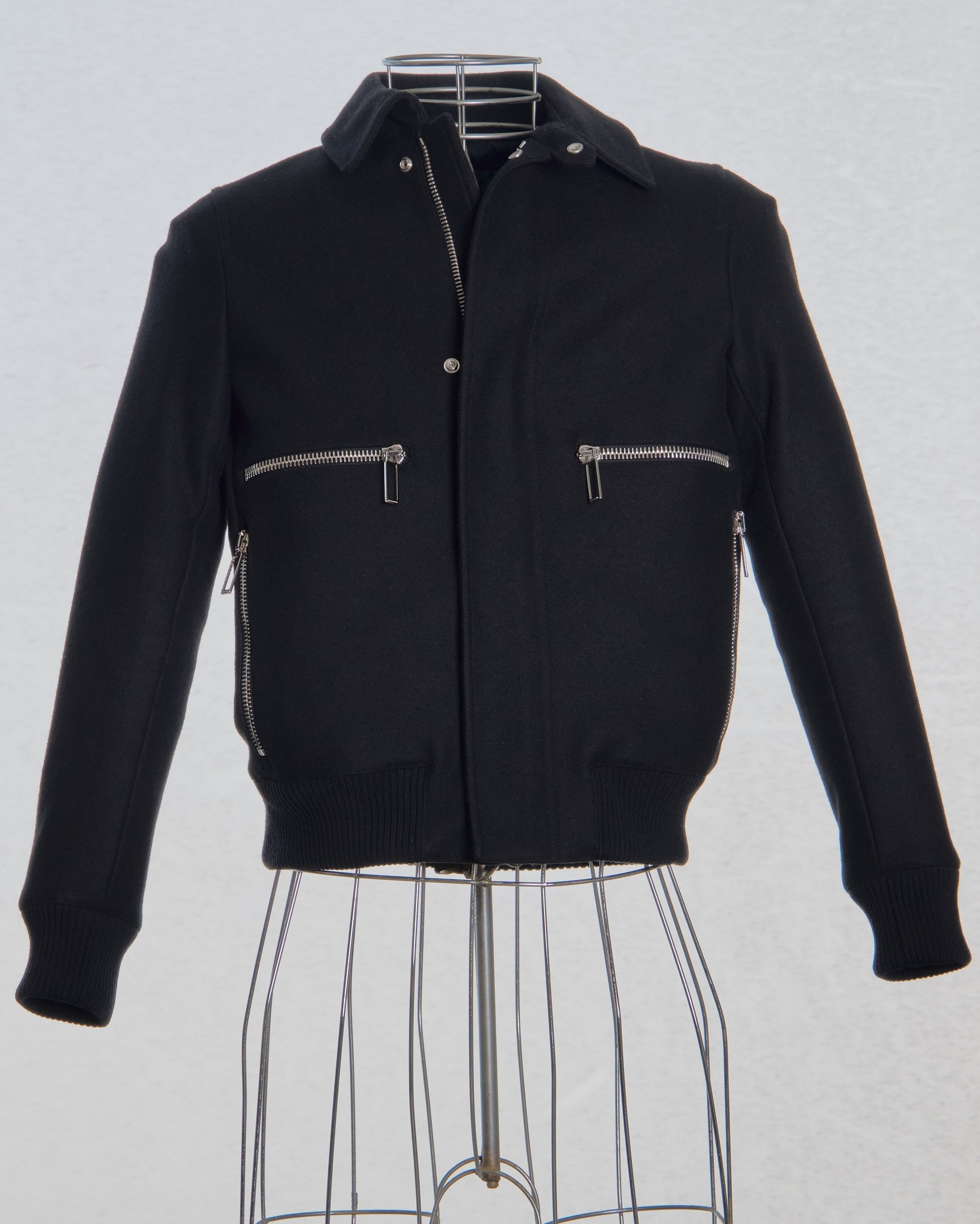Black Dior jacket with zippers on a mannequin against a light gray background