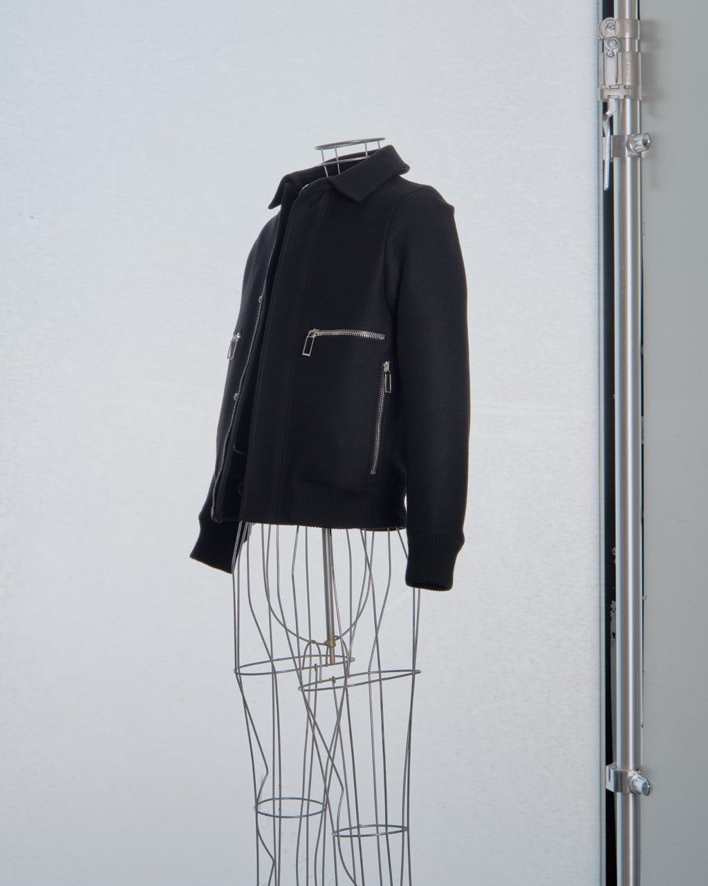 Black Dior jacket on a wire mannequin against a plain background