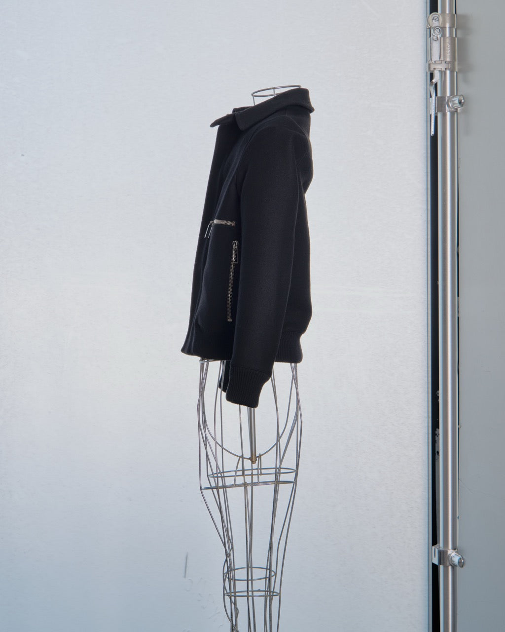 Black Dior jacket on a wire mannequin against a light gray background