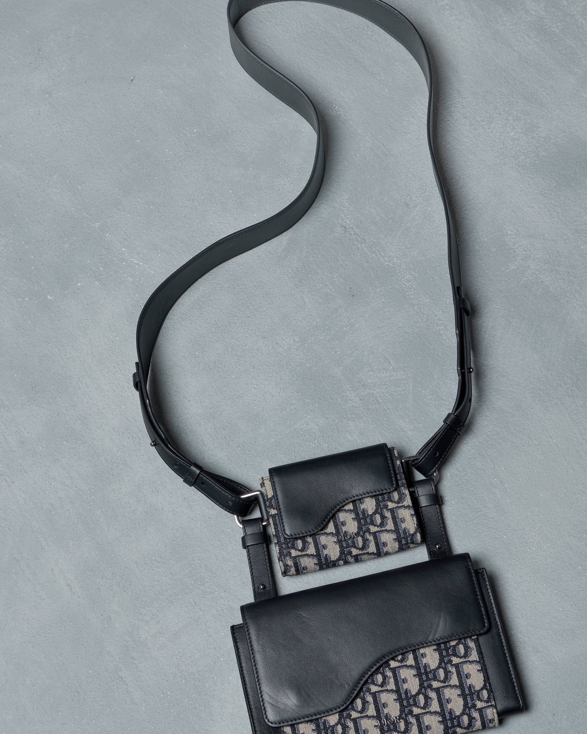 Black Dior handbag with patterned design on a gray background