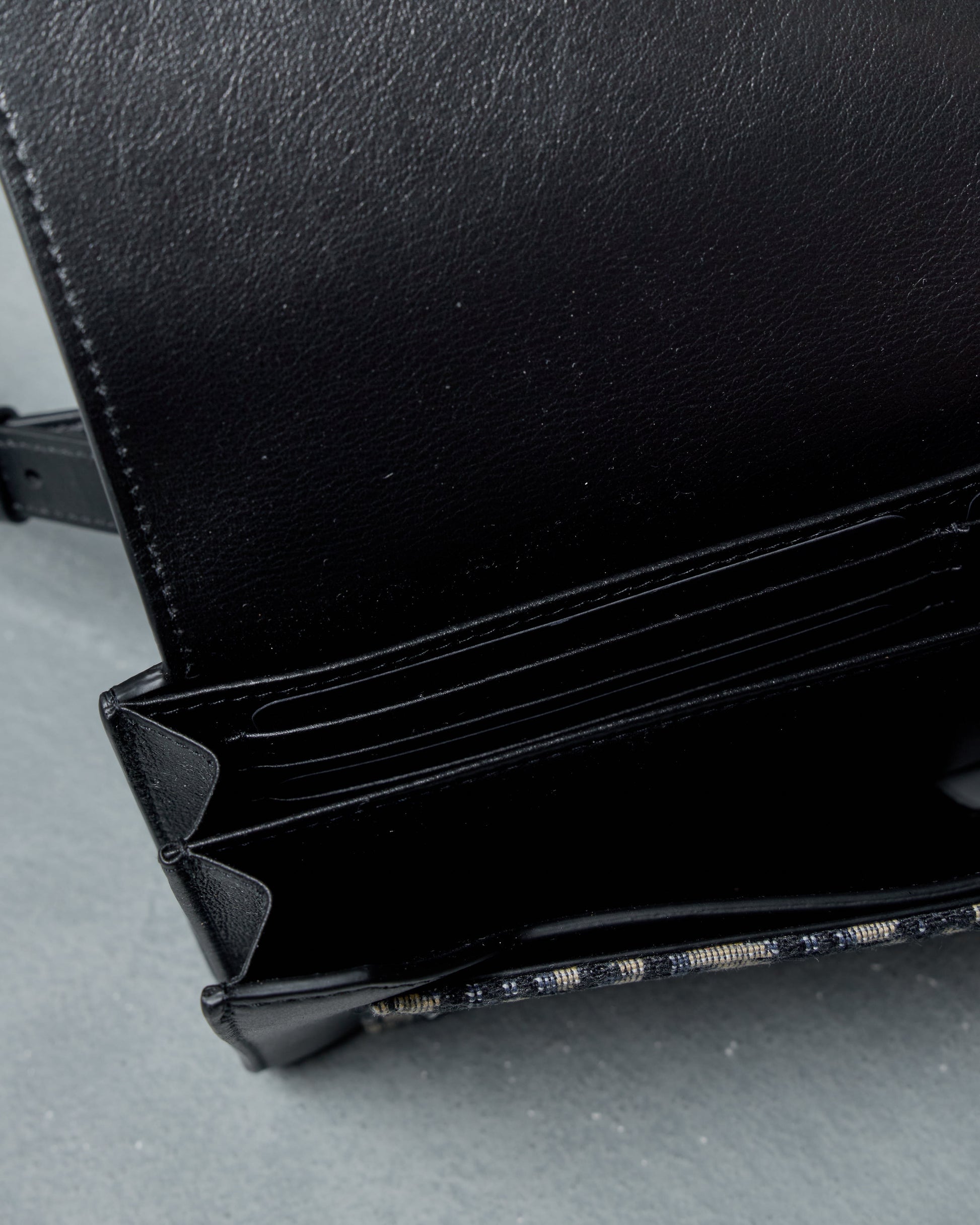 Internal view of Black leather in Dior cross body bag on a gray surface