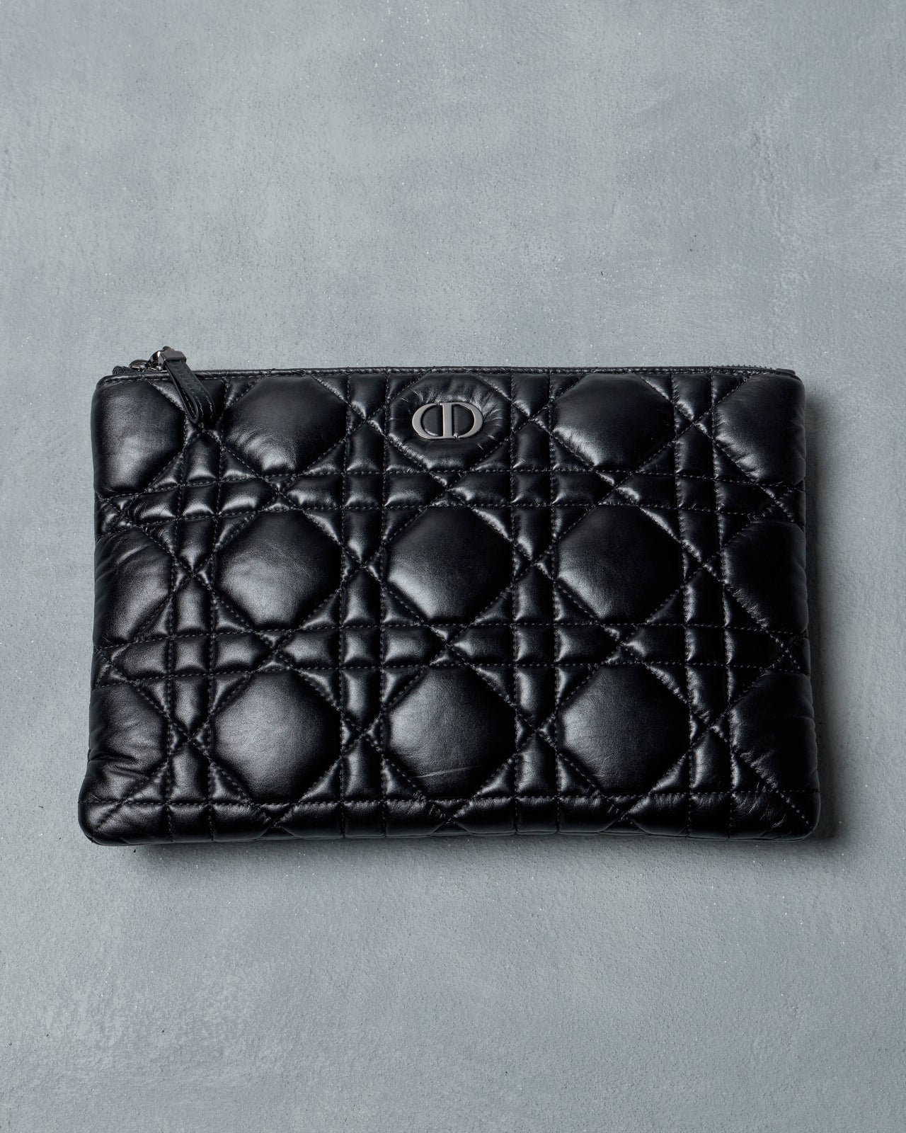 Black quilted Dior leather pouch on a gray background