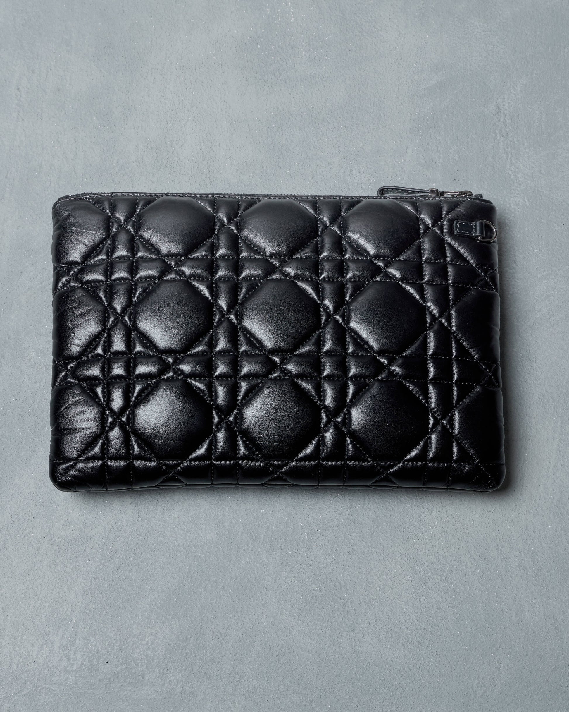 Black quilted leather Dior pouch on a gray background