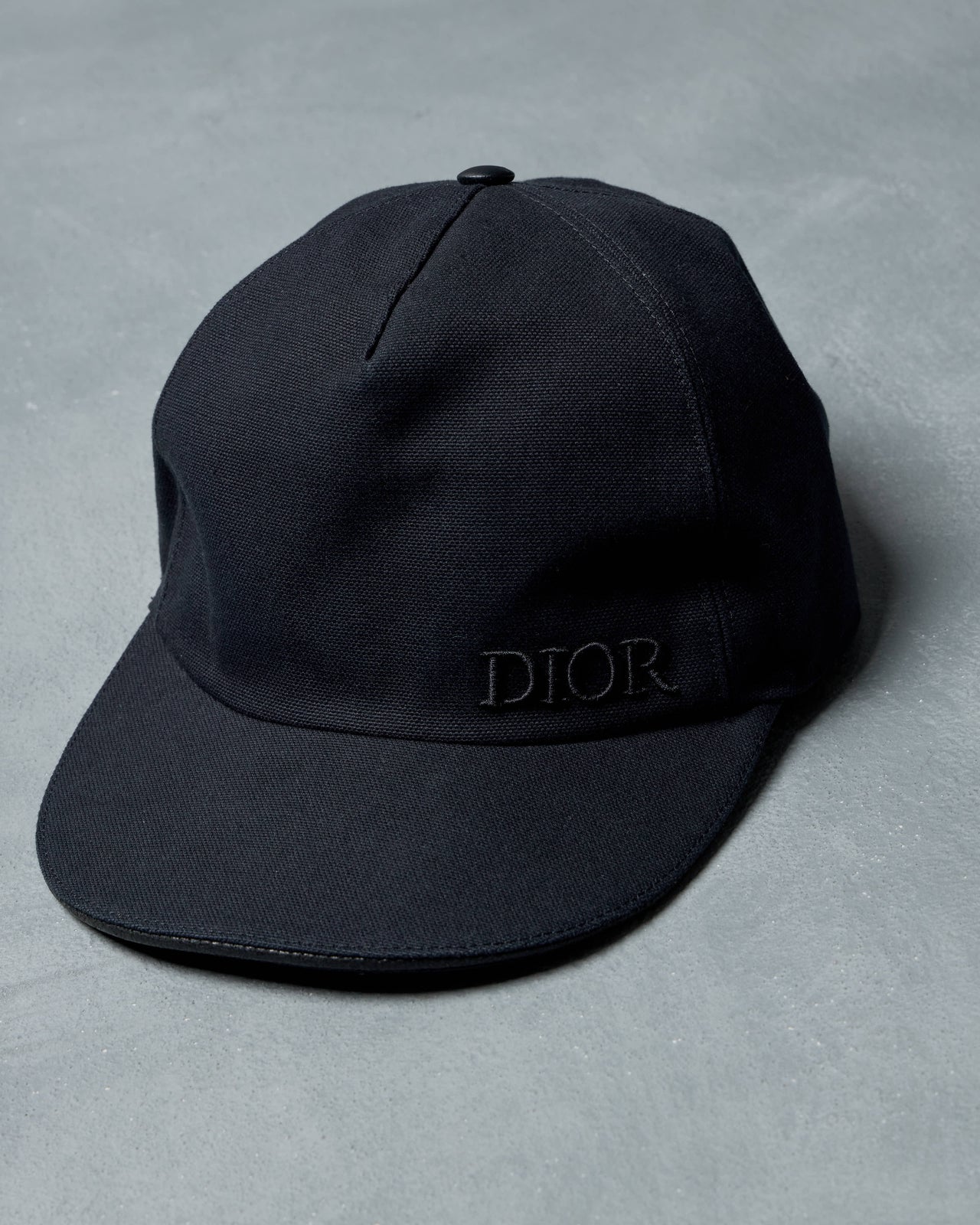Black Dior cap with a brand logo on a gray background