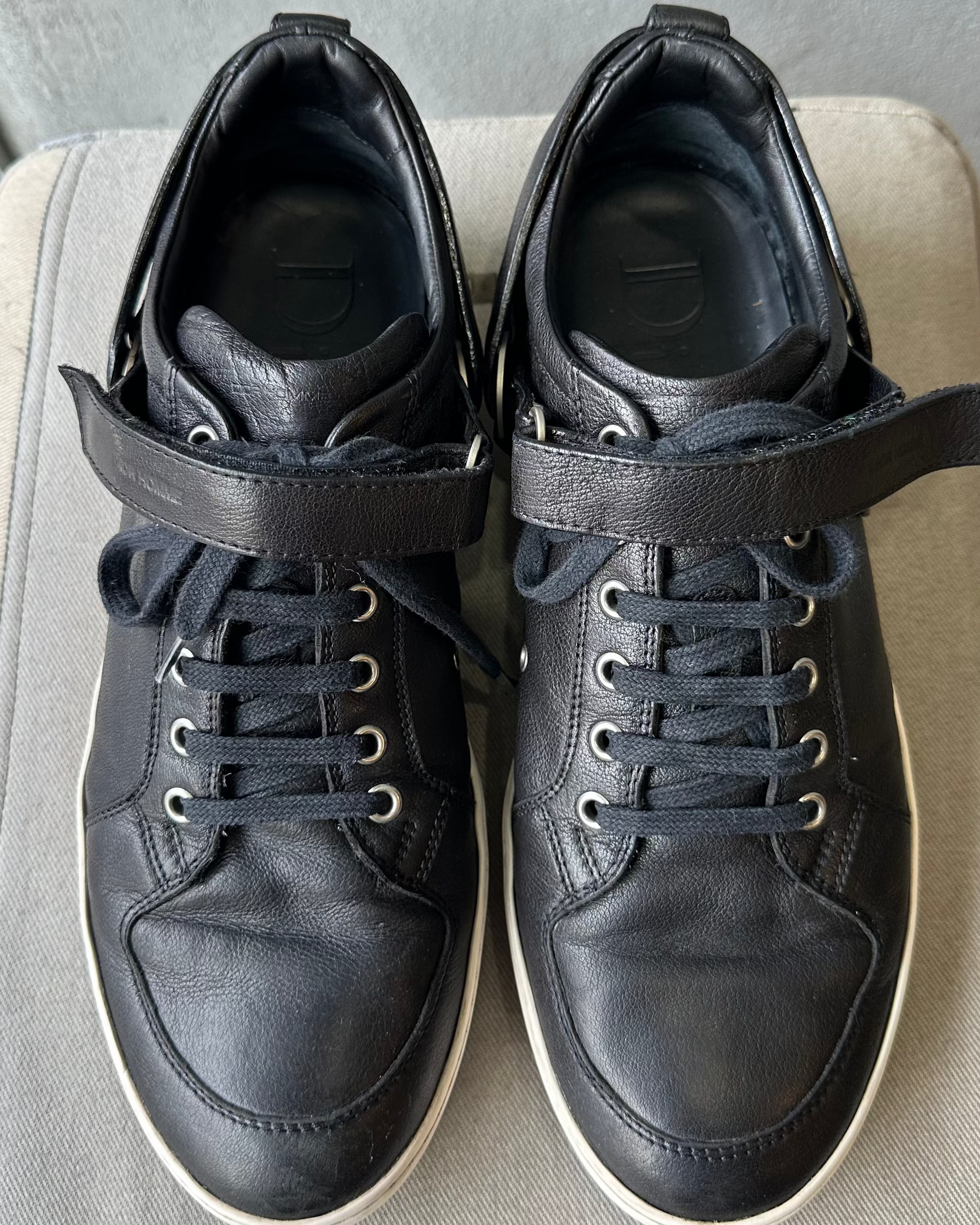Pair of black high-top Dior Homme sneakers on a light gray surface with a neutral background