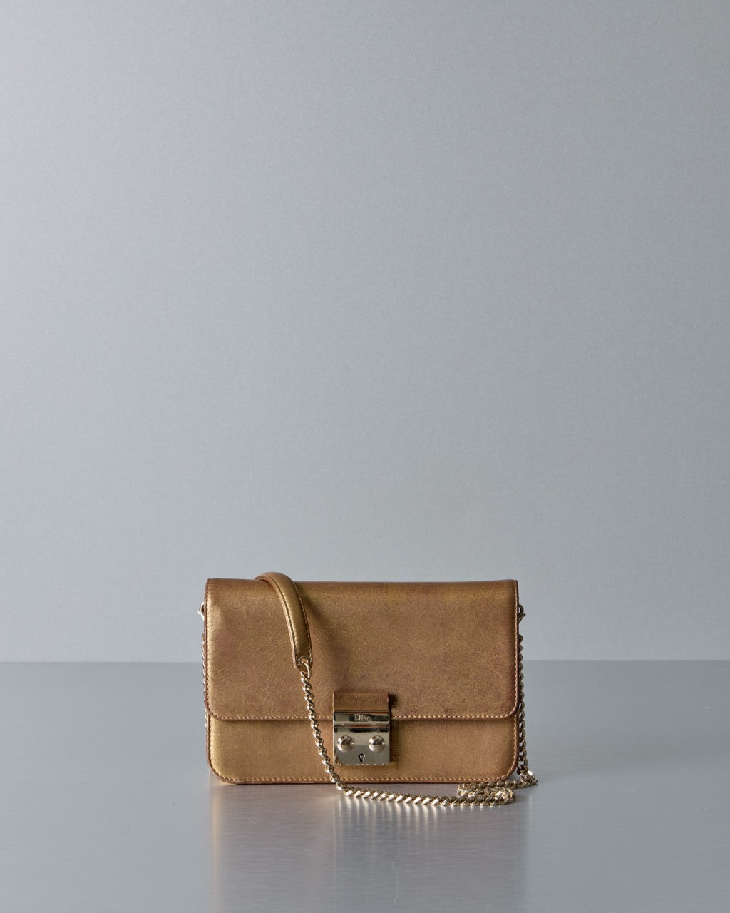 Gold Dior handbag with a chain detail on a gray background