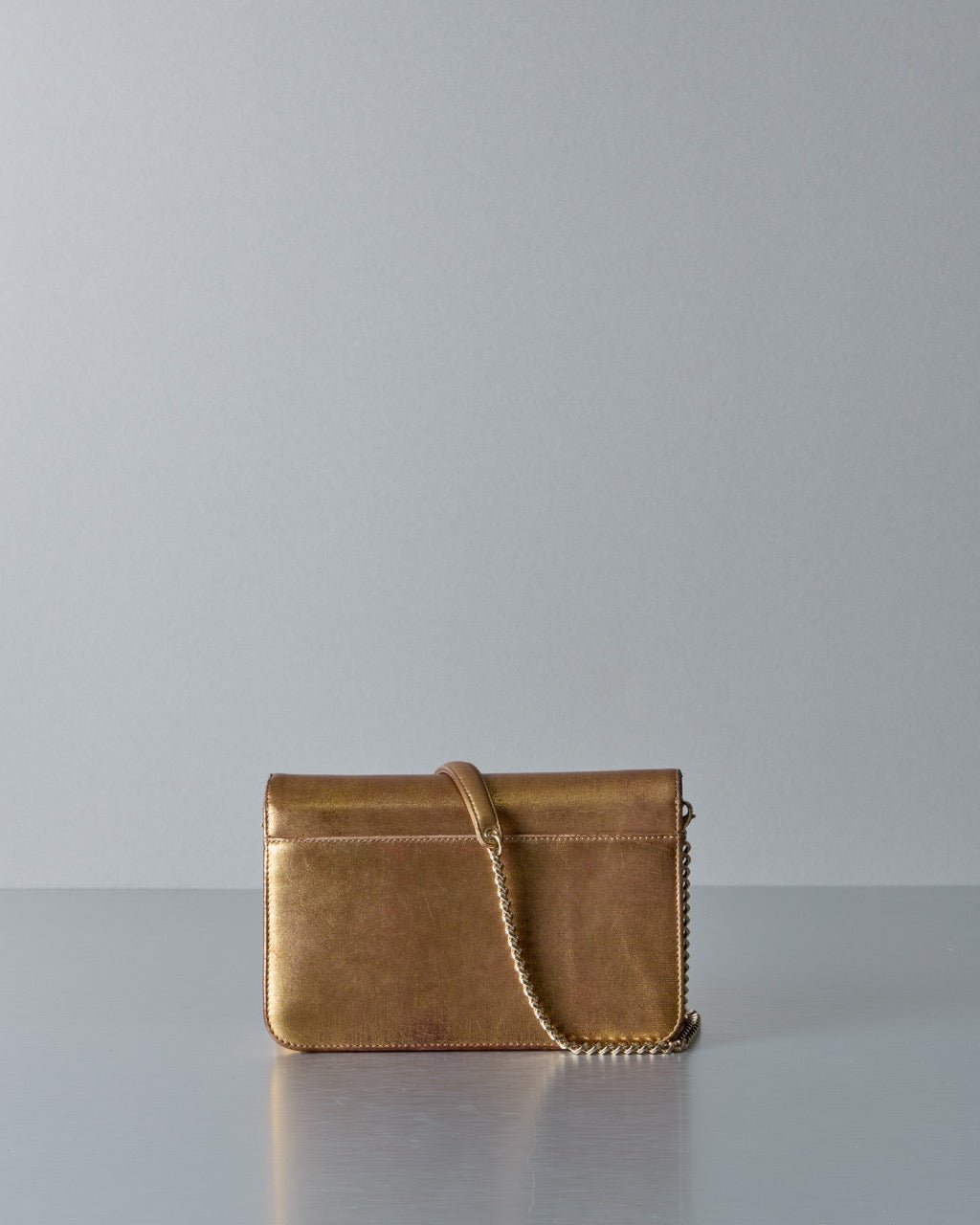 Gold Dior leather handbag with chain detail on a gray background