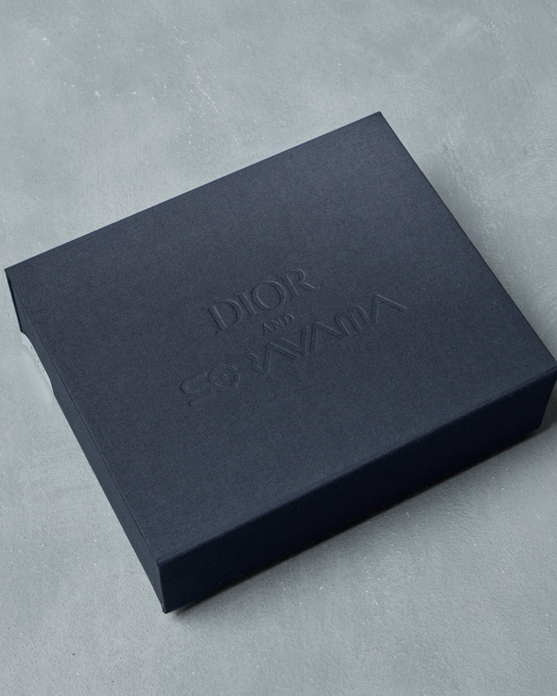 Black Dior box on a gray concrete surface