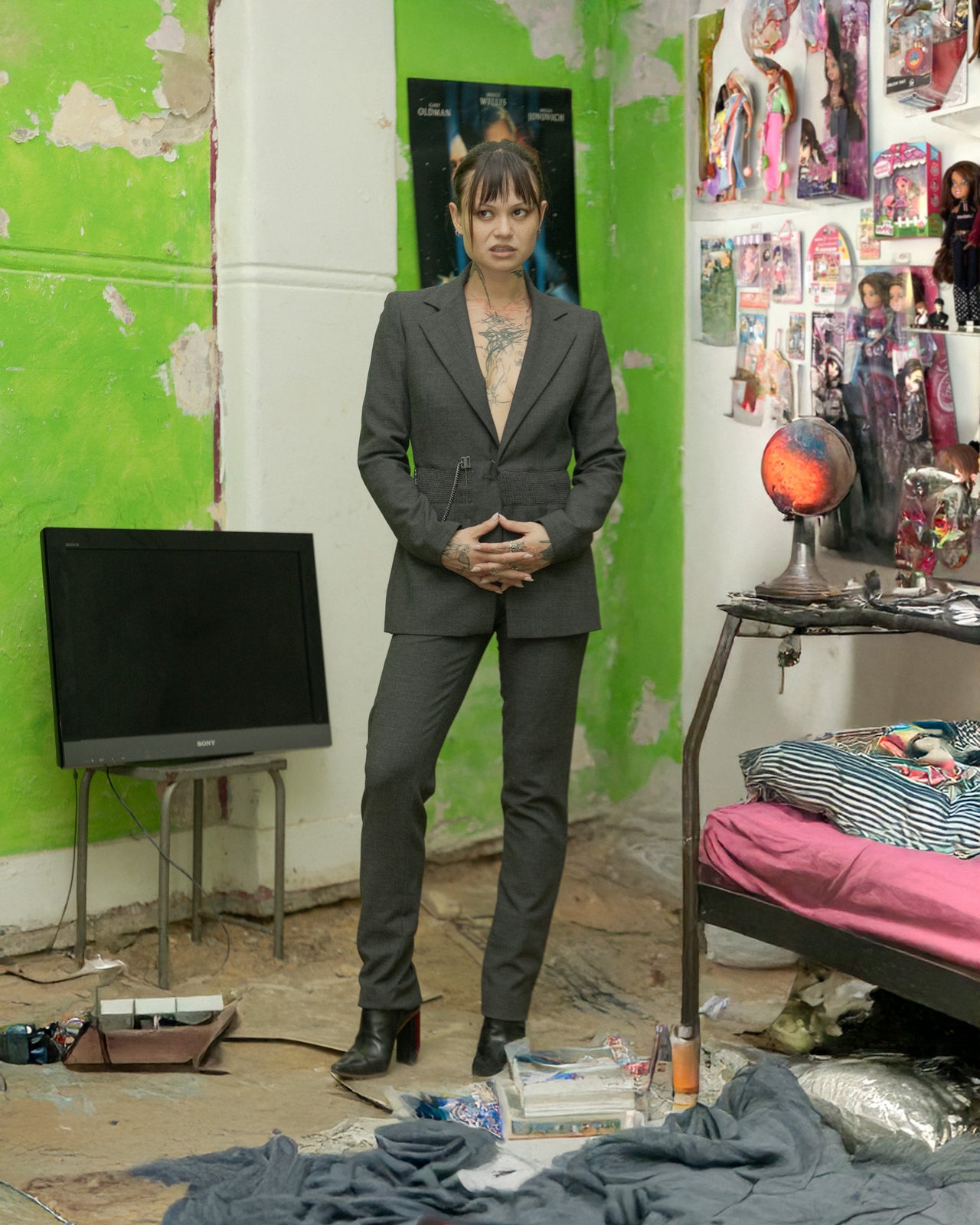 A person wearing a Dirk Bikkembergs two-piece suit with a chain detail, standing in a room with colorful walls and various items around.