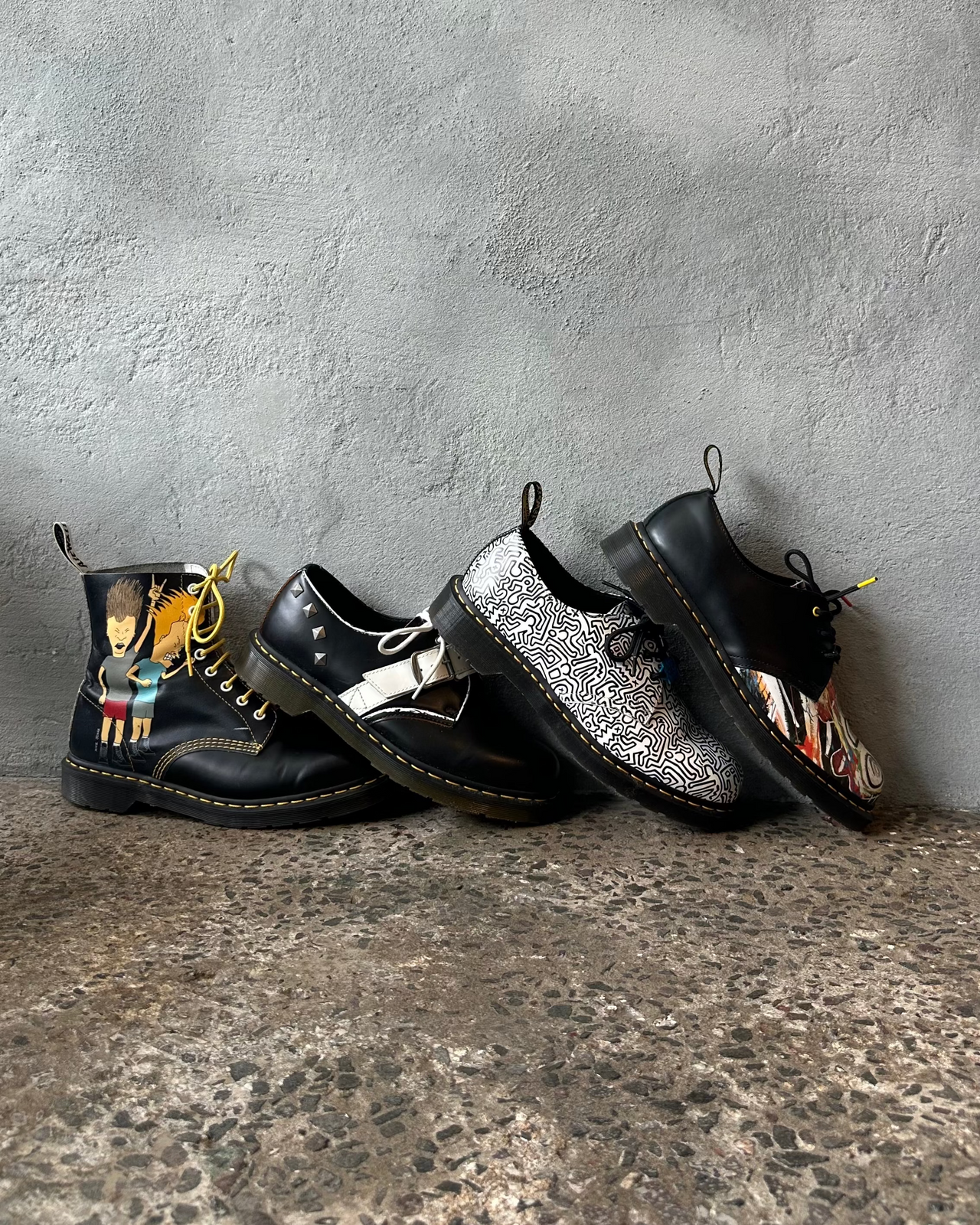 Black doc martens boot with colorful graphic design on a textured surface and gray background