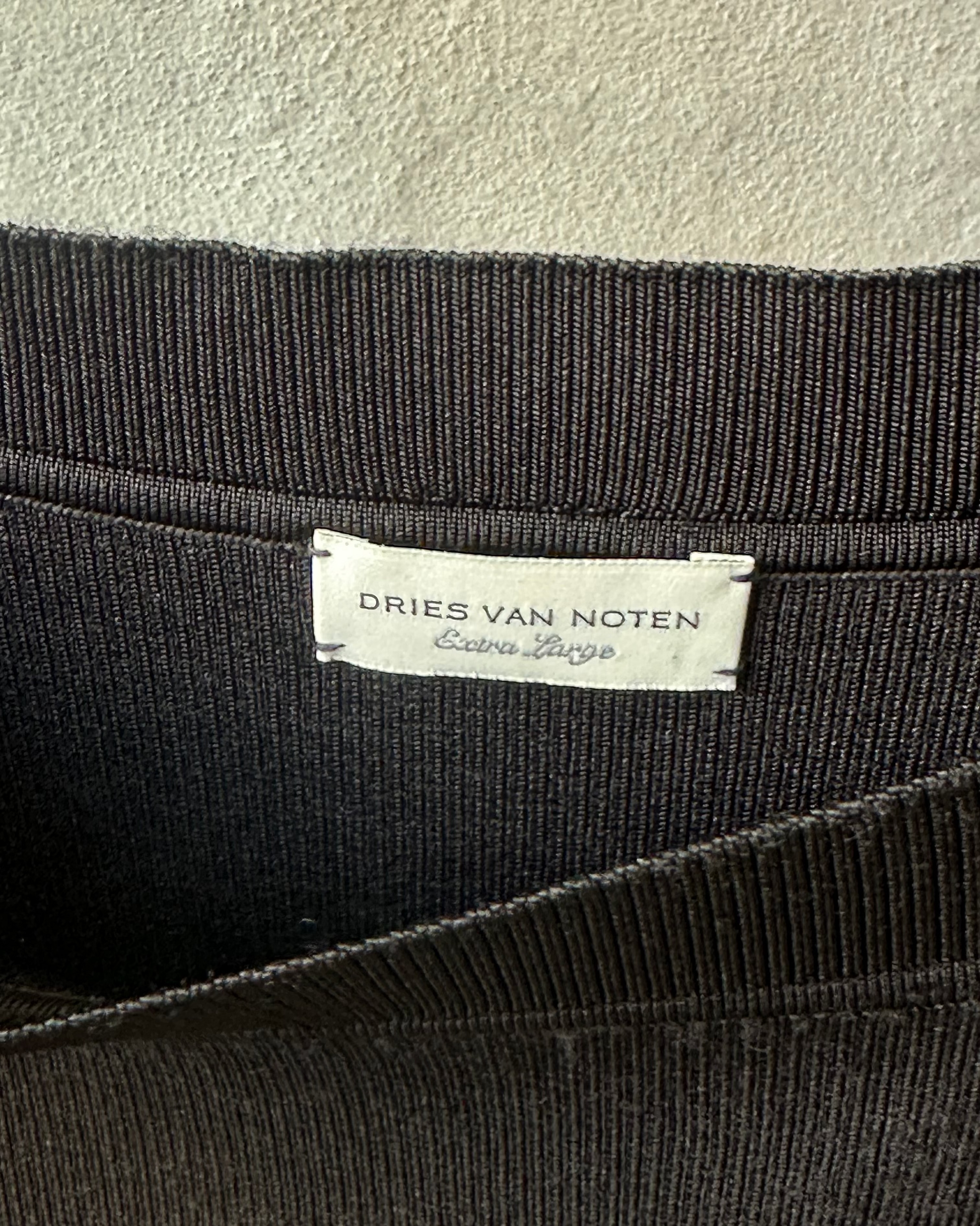 Close-up of a black fabric with a Dries Van Noten label on a beige background