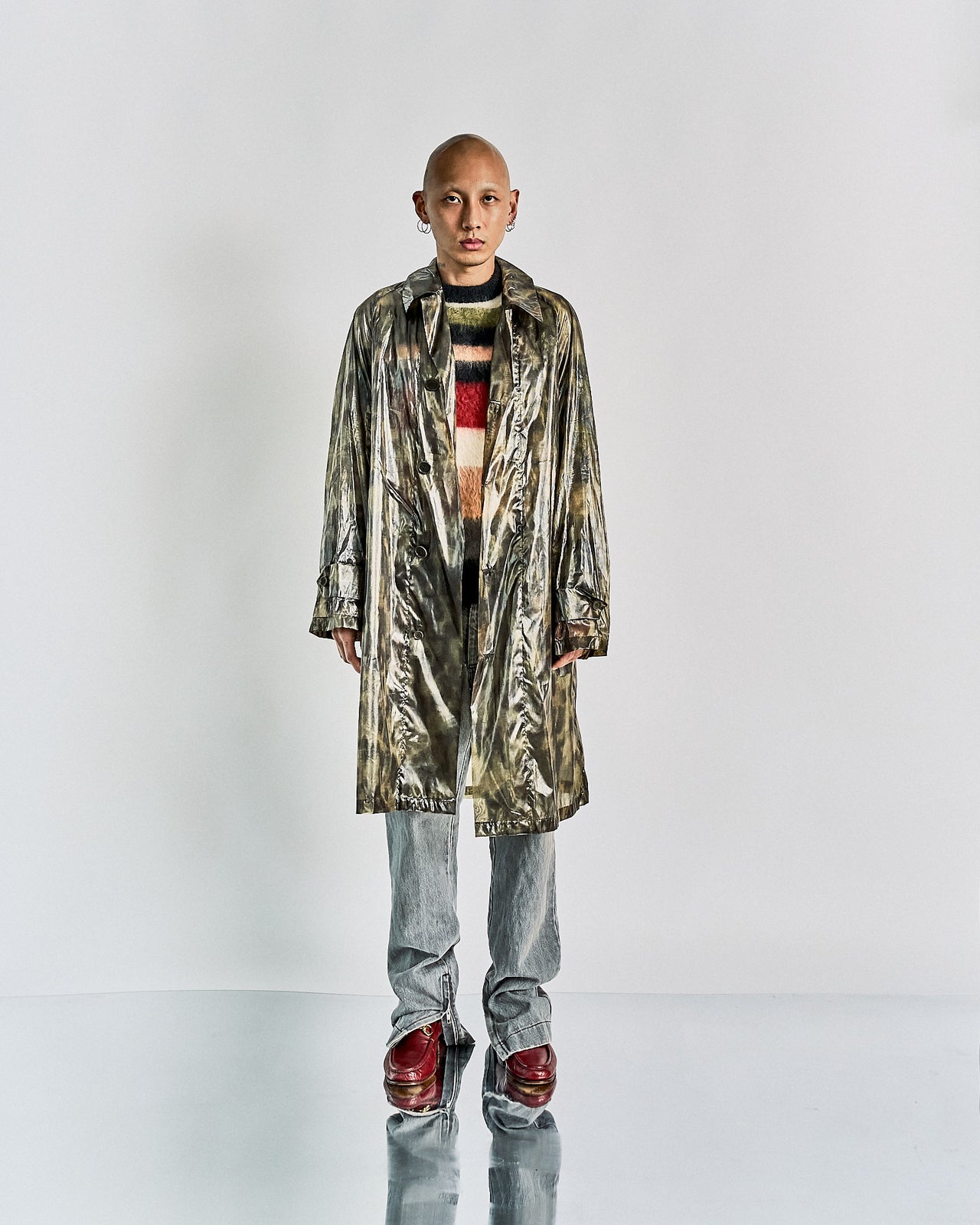 A person modeling a Dries Van Noten SS 2013 Silk camouflage coat with button-up details and raglan shoulders, featuring hip pockets and wood grain buttons.