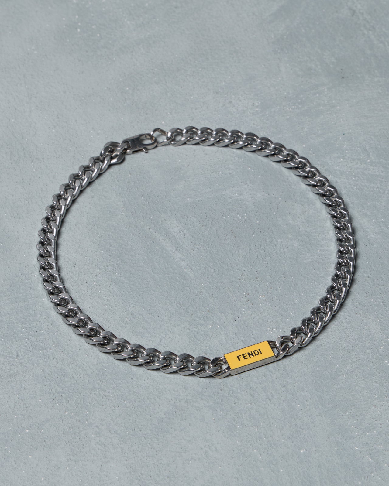 Silver chain Fendi necklace with a yellow tag on a gray background