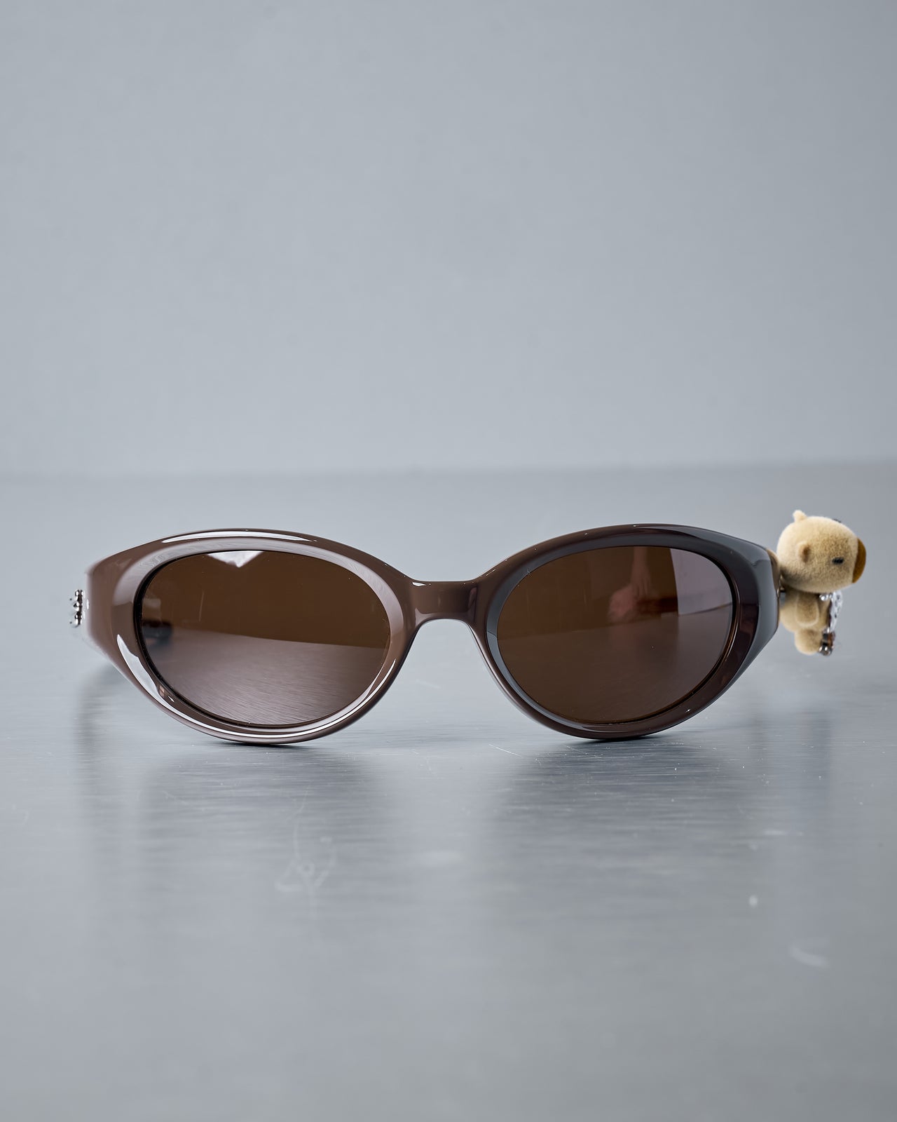 Gentle Monster x Jennie sunglasses with a small bear figurine attached on a reflective surface