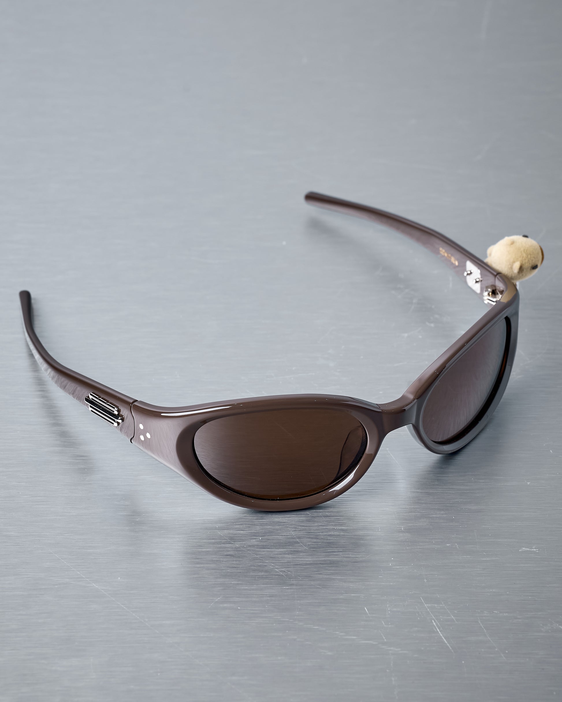 Gentle Monster x Jennie brown sunglasses on a reflective grey surface