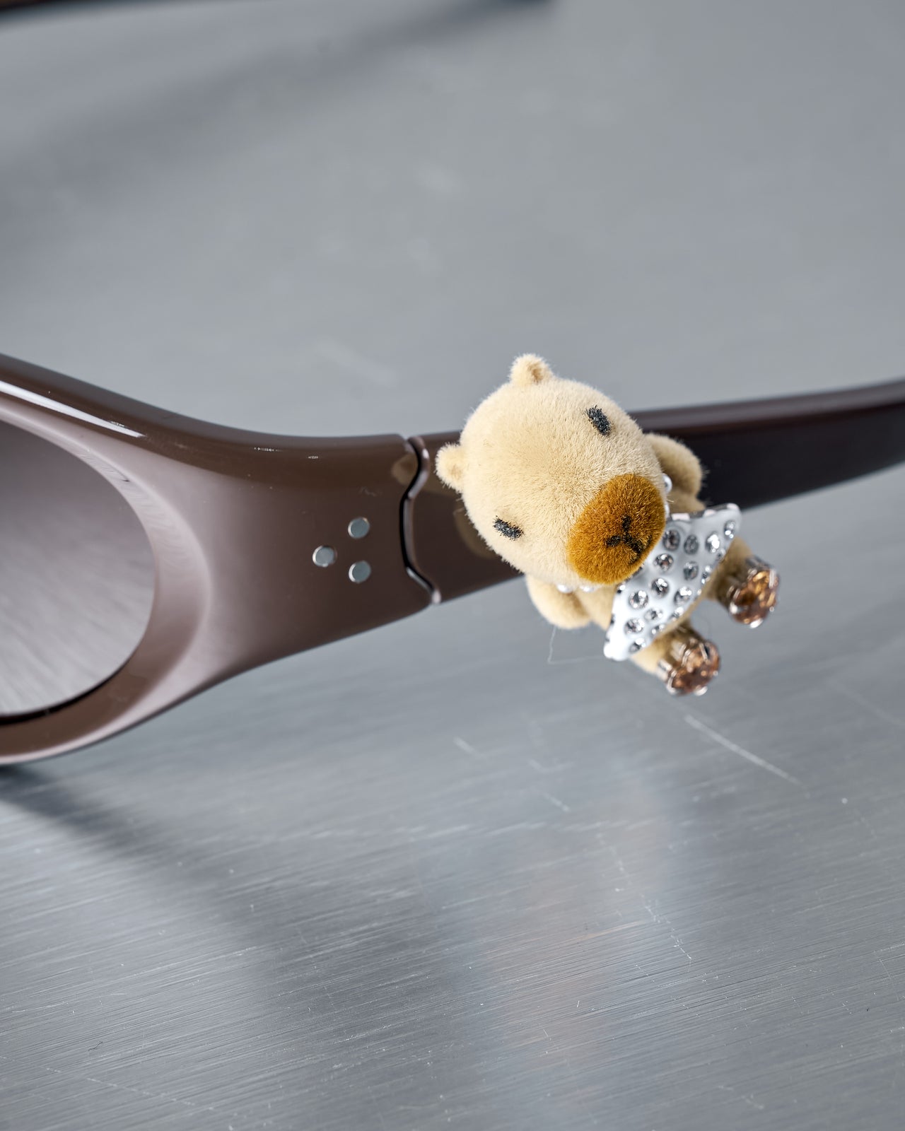 Gentle Monster x Jennie sunglasses with a small bear figurine attached on a reflective surface