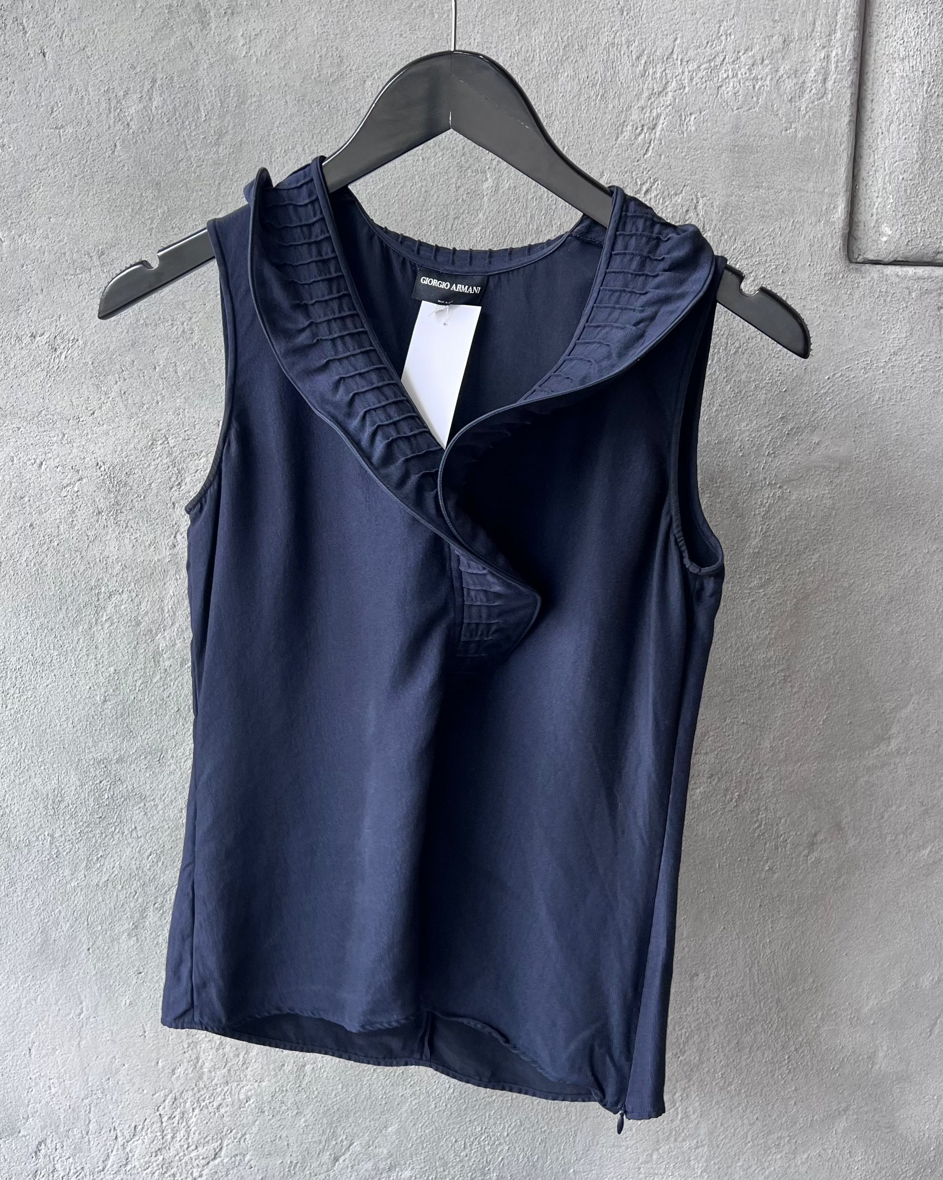 Navy blue Giorgio Armani tank top on a hanger against a gray wall