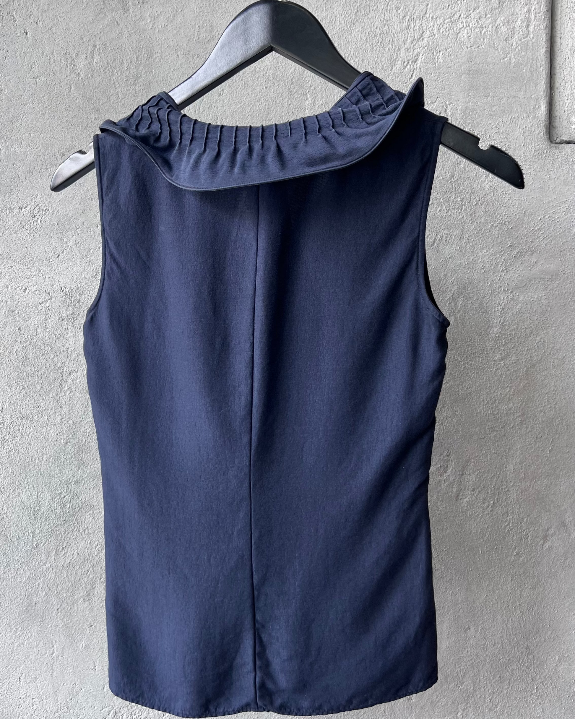 Navy blue Giorgio Armani sleeveless top on a hanger against a gray wall