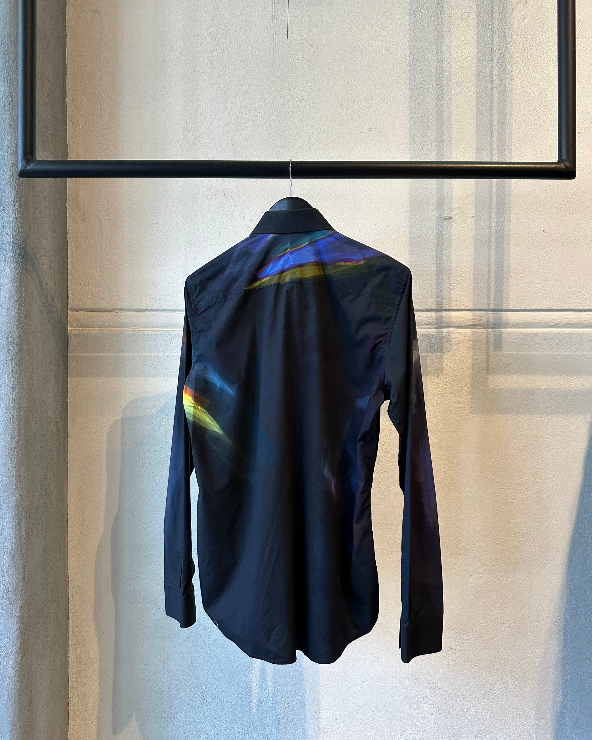 Black Givenchy shirt with colorful accents on a hanger against a neutral background