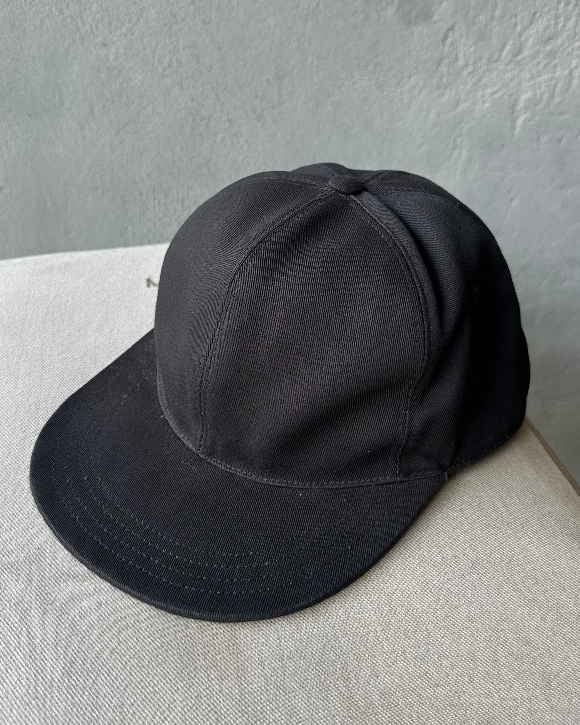 Black Givenchy cap on a textured surface with a gray background