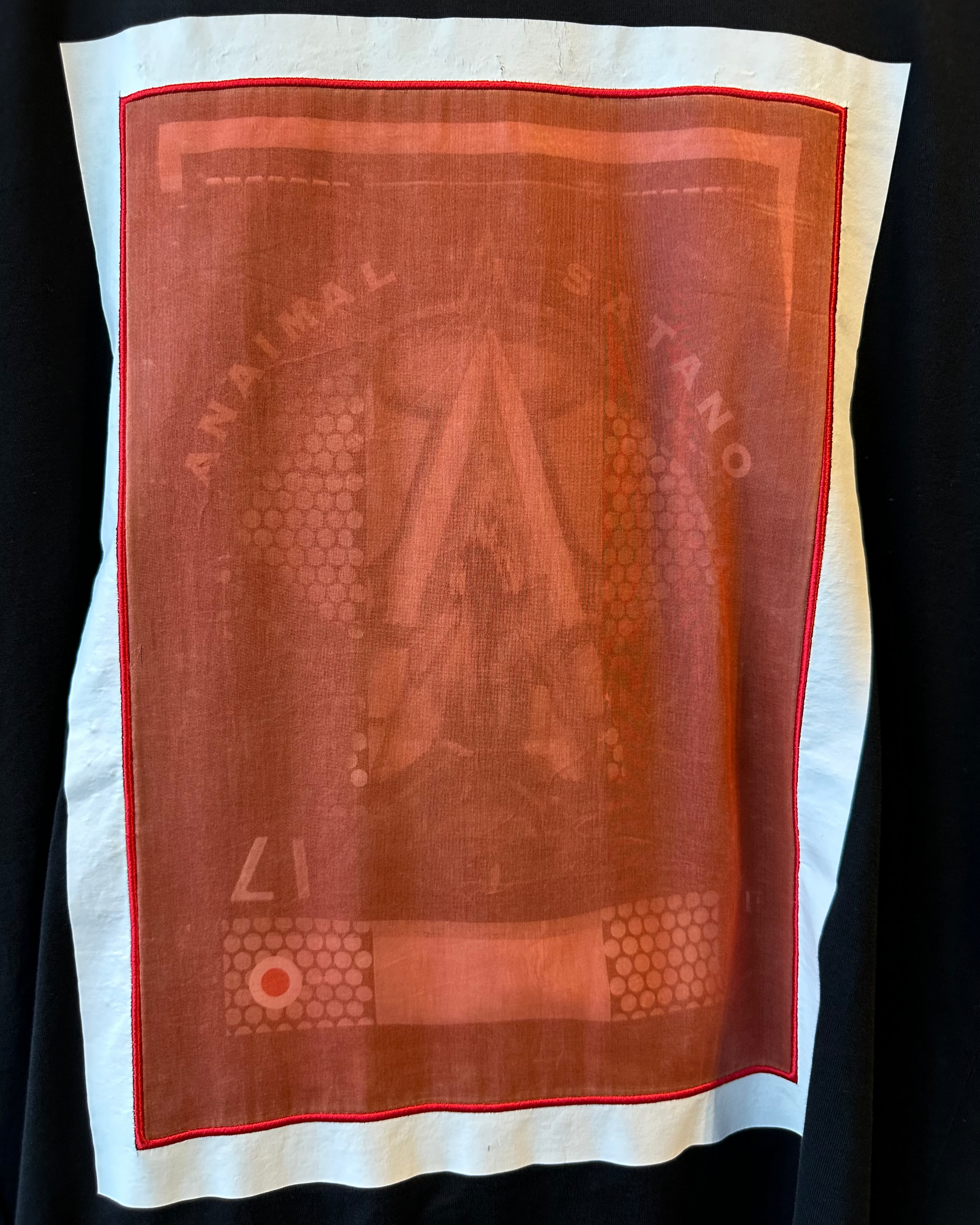 Closeup of Givenchy tshirt with a central red design and text on a plain background