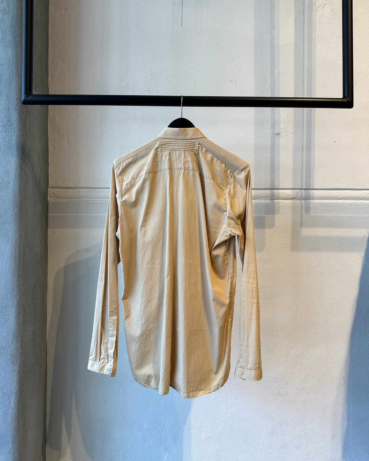 Beige Givenchy shirt on a hanger against a neutral background
