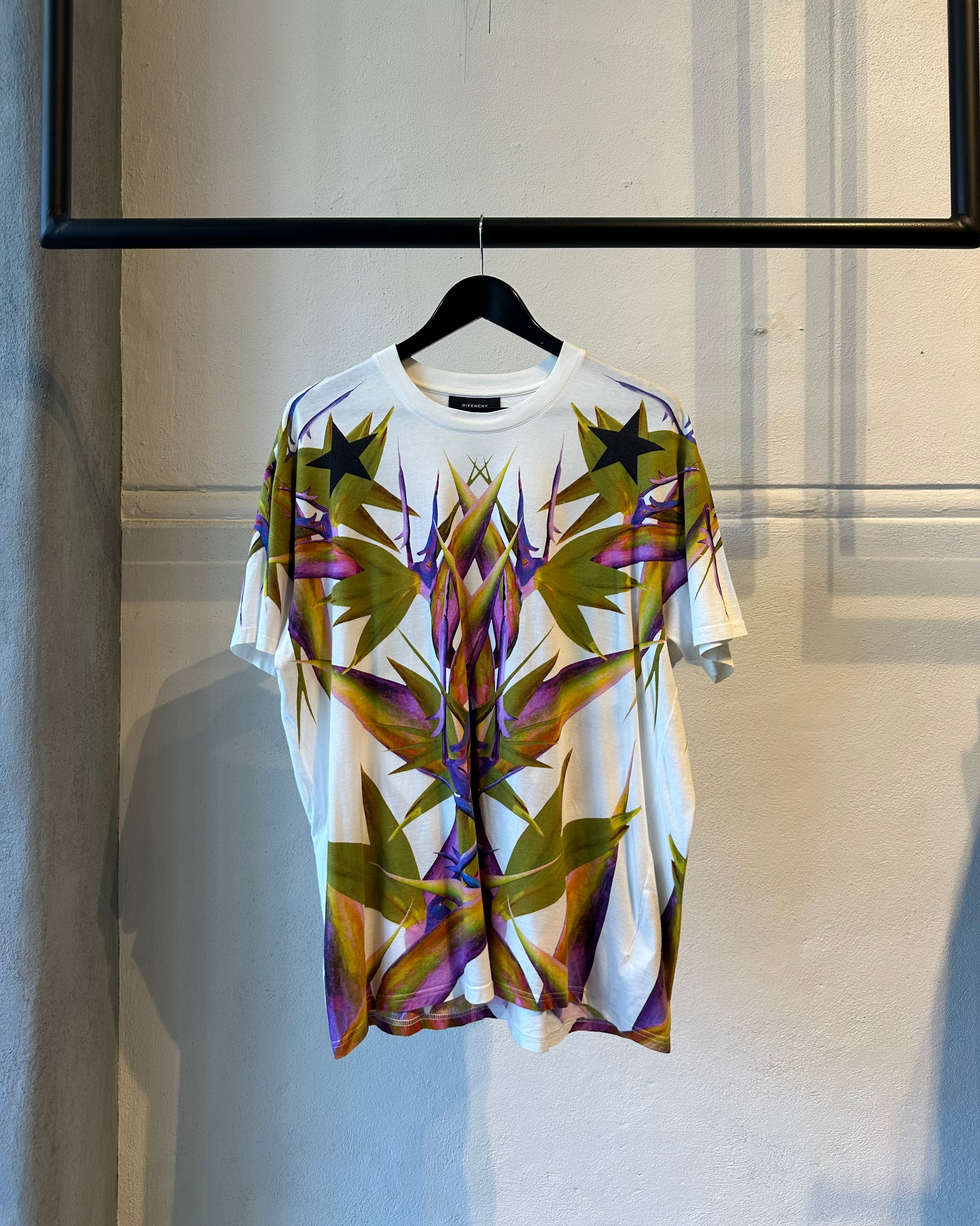 Colorful Givenchy t-shirt with abstract design on a hanger against a neutral background
