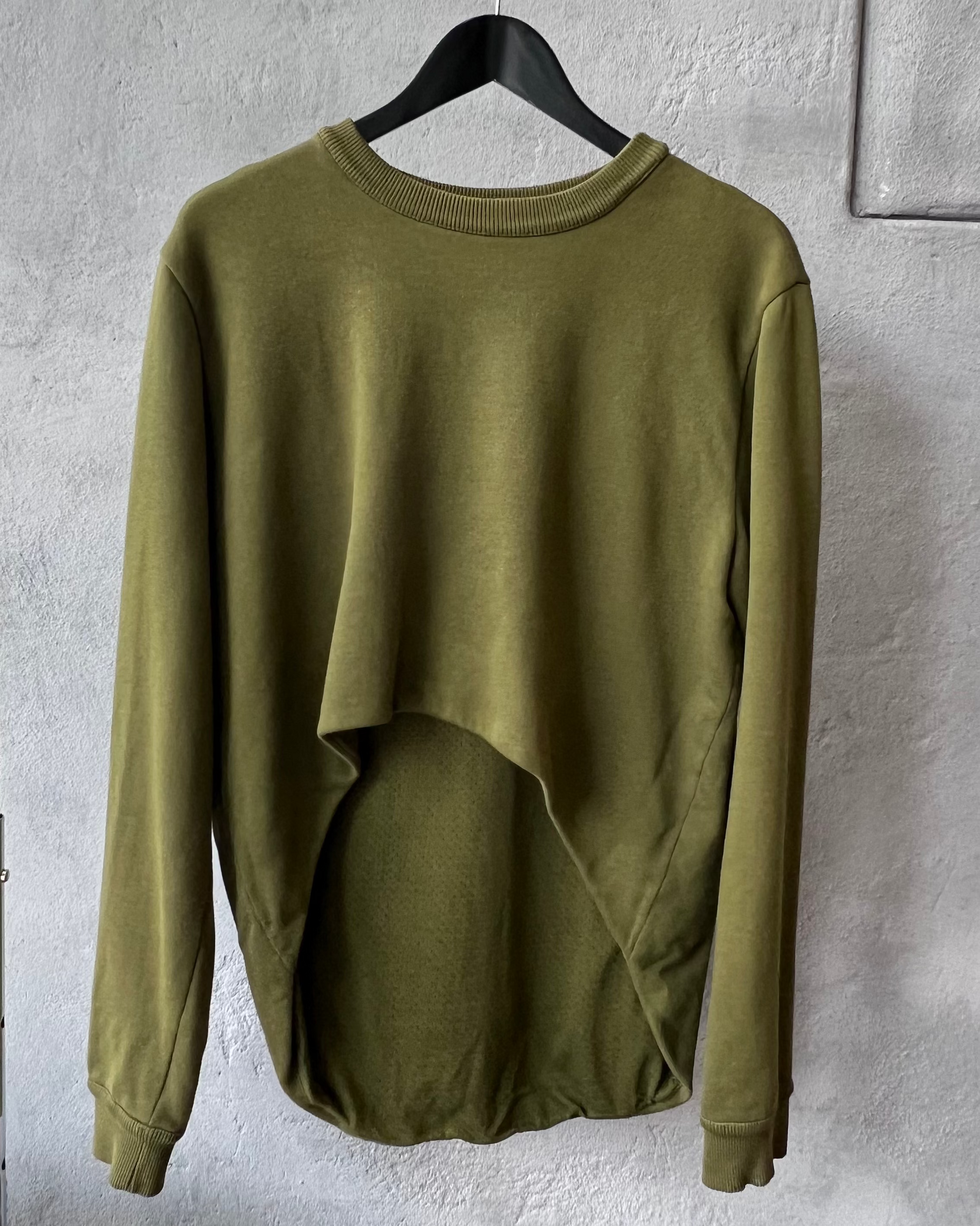 Green Givenchy sweatshirt on a hanger against a gray textured wall