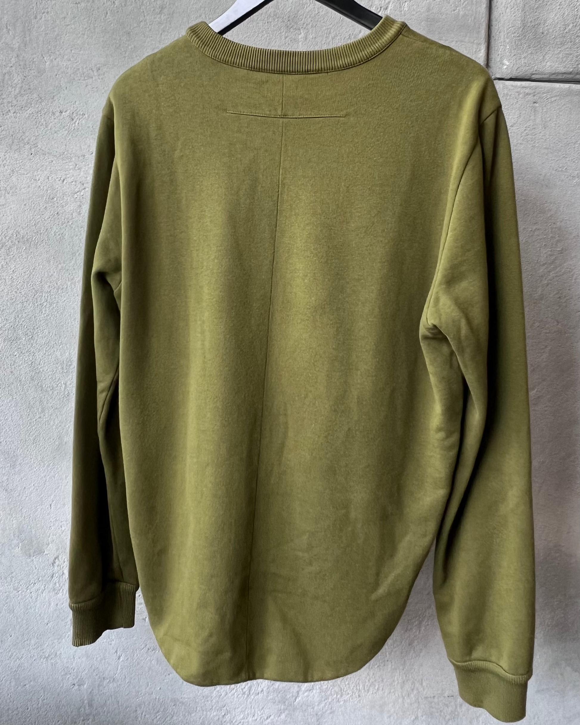 Green long-sleeve Givenchy shirt on a hanger against a gray wall