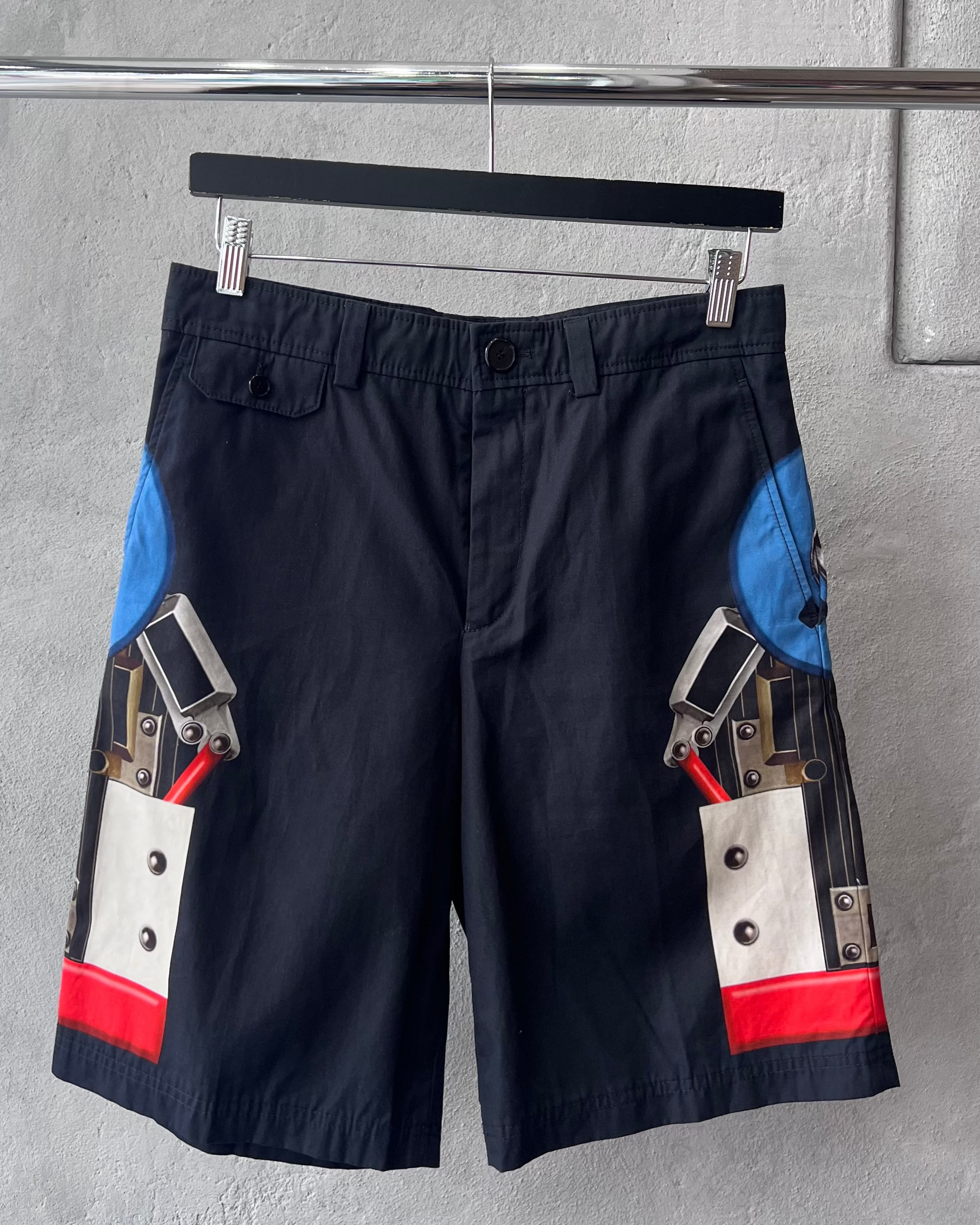 Black Givenchy shorts with colourful graphic design on a gray wall background