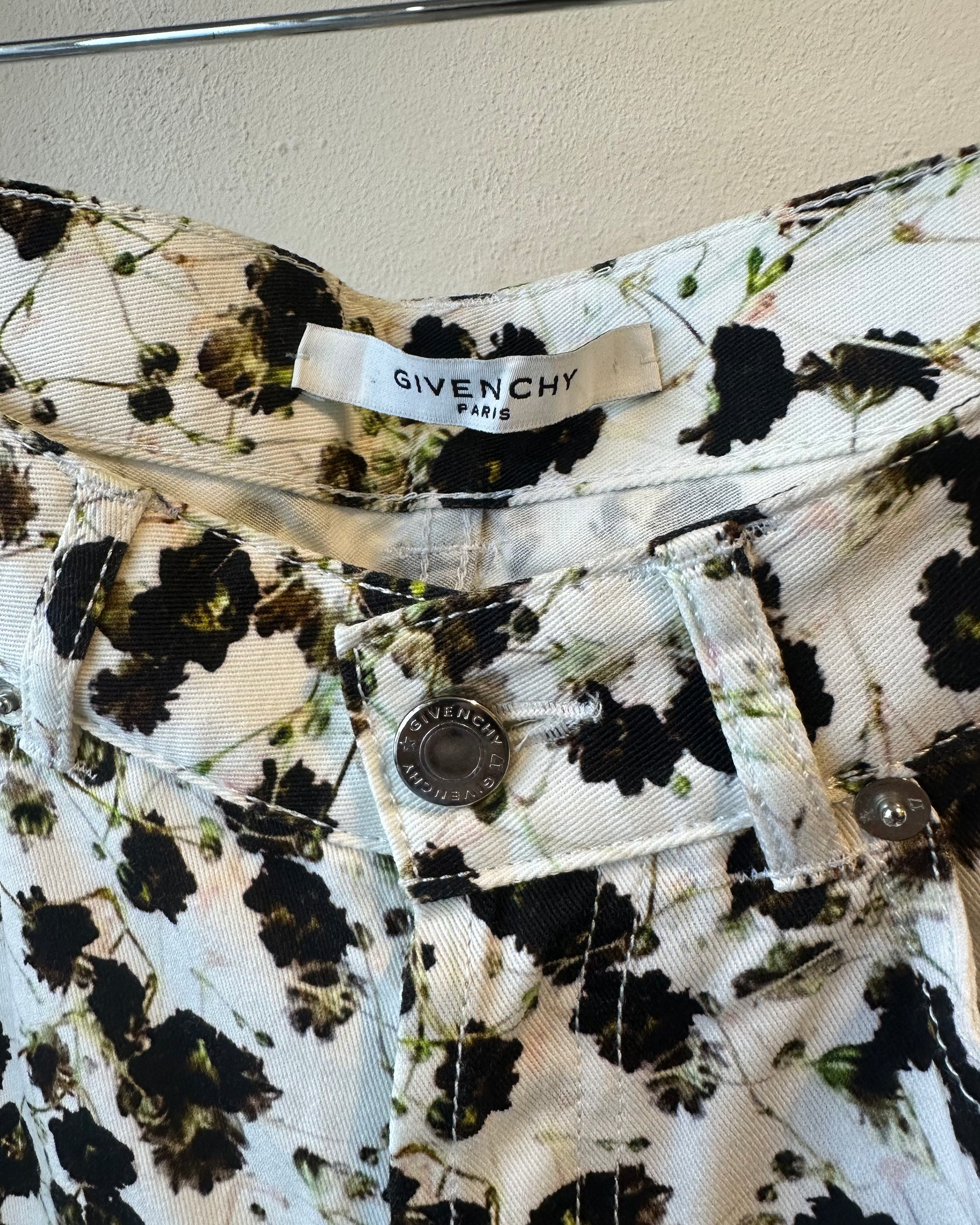 Floral-patterned pants with Givenchy label on a beige wall background