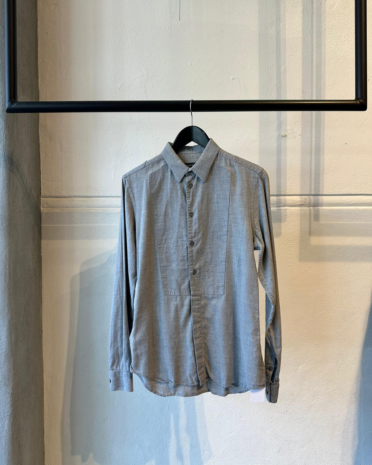 Gray Givenchy button-up shirt on a hanger against a light-colored wall.