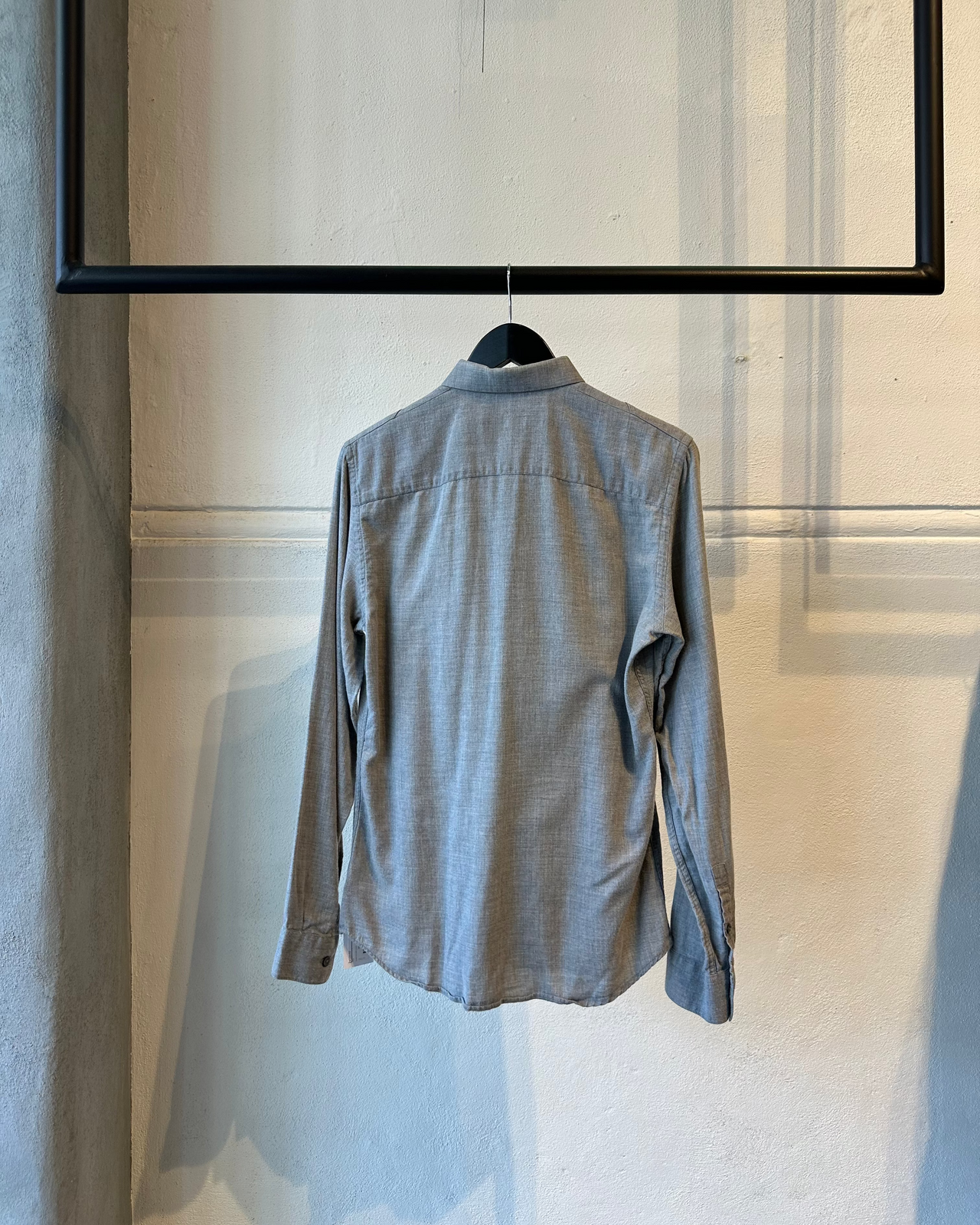 Gray Givenchy button-up shirt on a hanger against a light-colored wall.