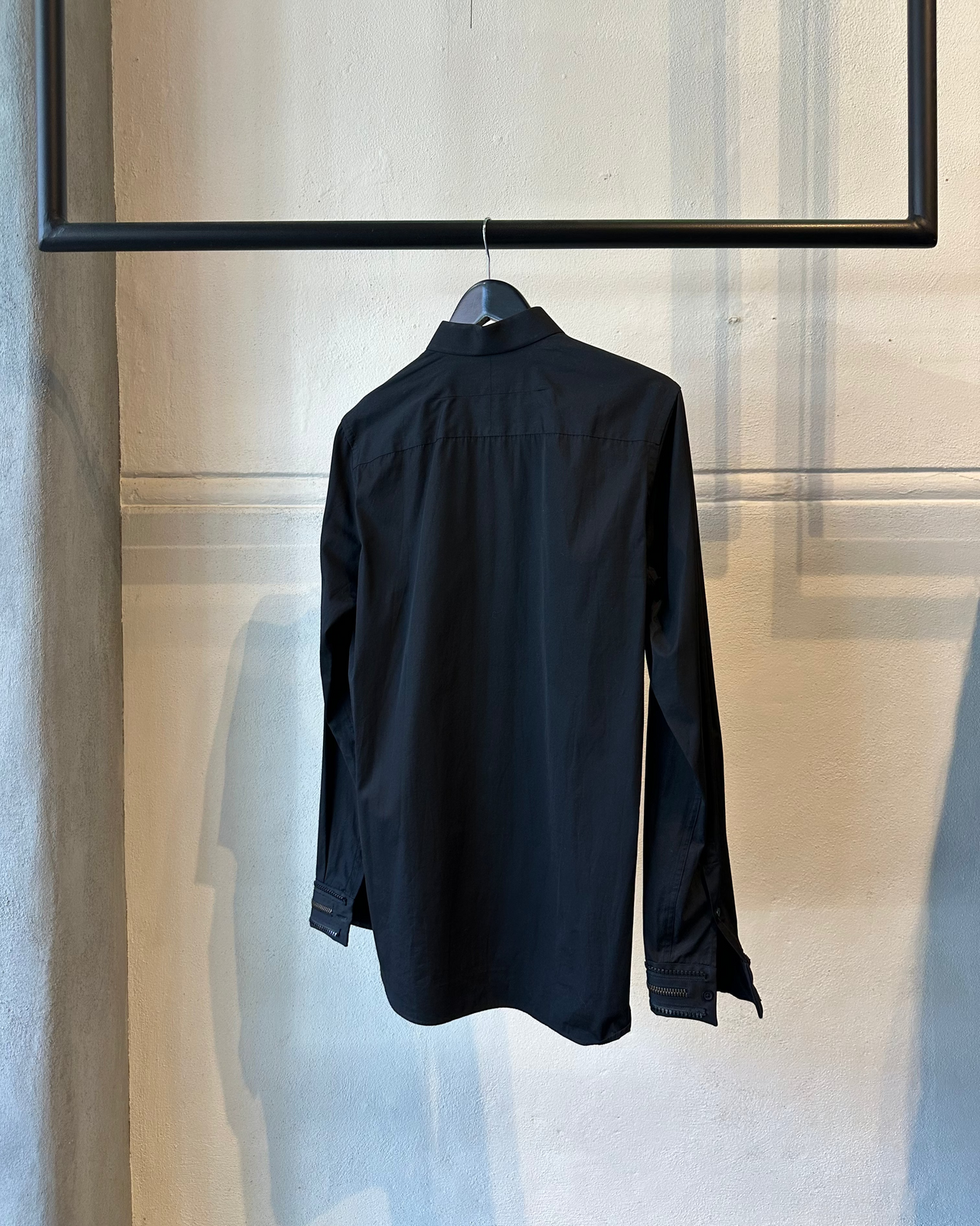 Black Givenchy shirt on a hanger against a neutral wall