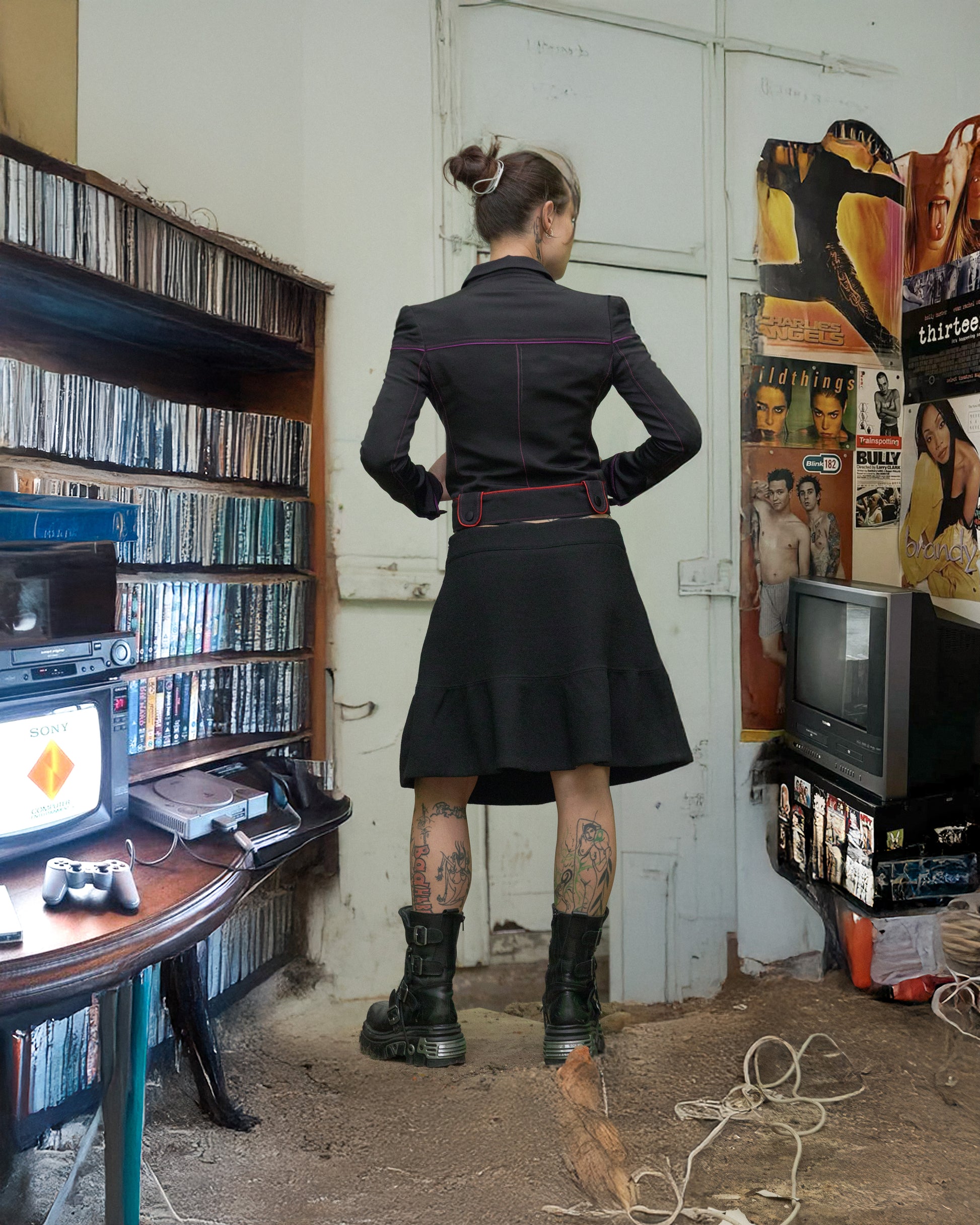 Person in a black Gucci outfit standing in a room with vintage decor, including a television and record player.