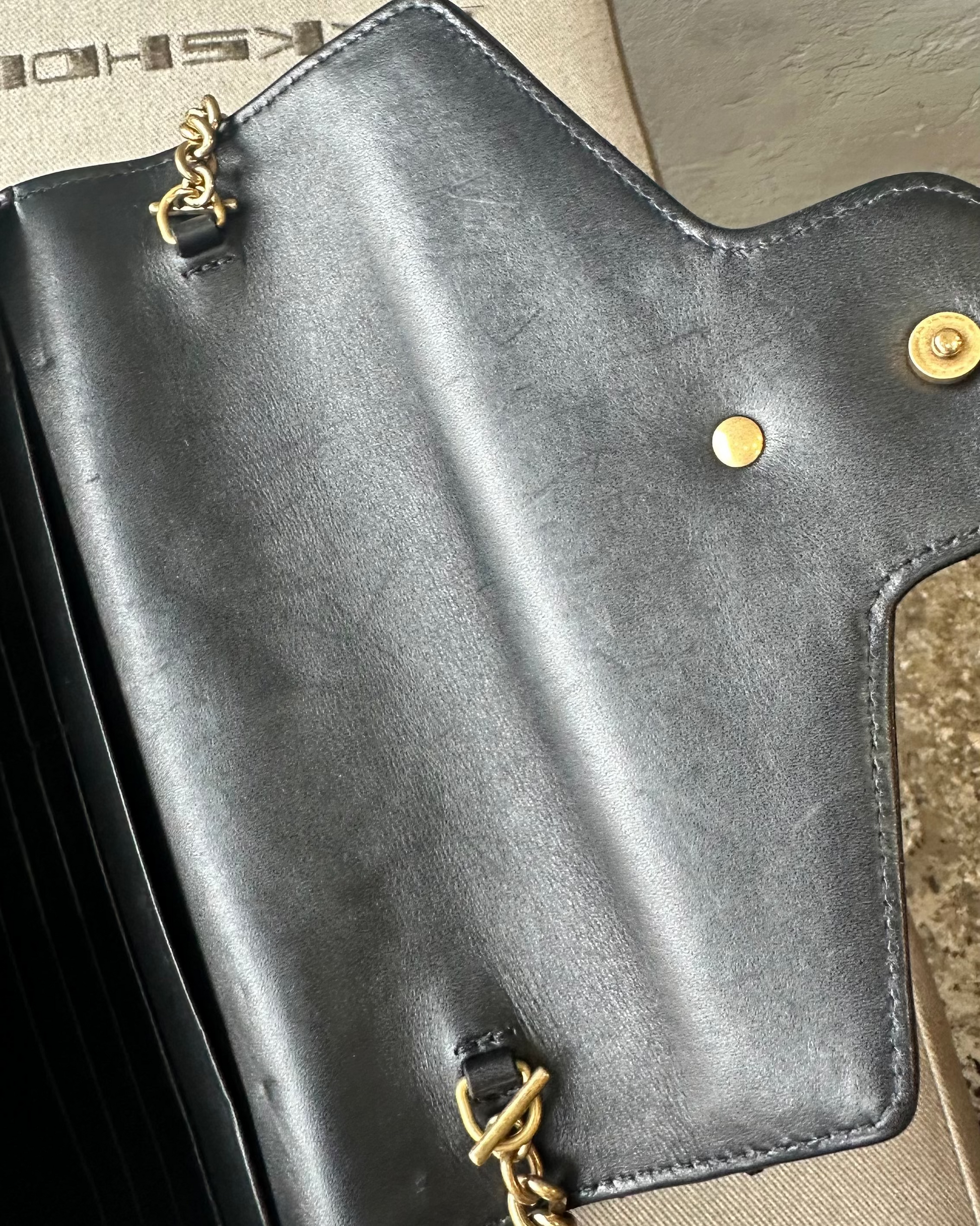 Black leather Gucci handbag with gold chain on a textured surface