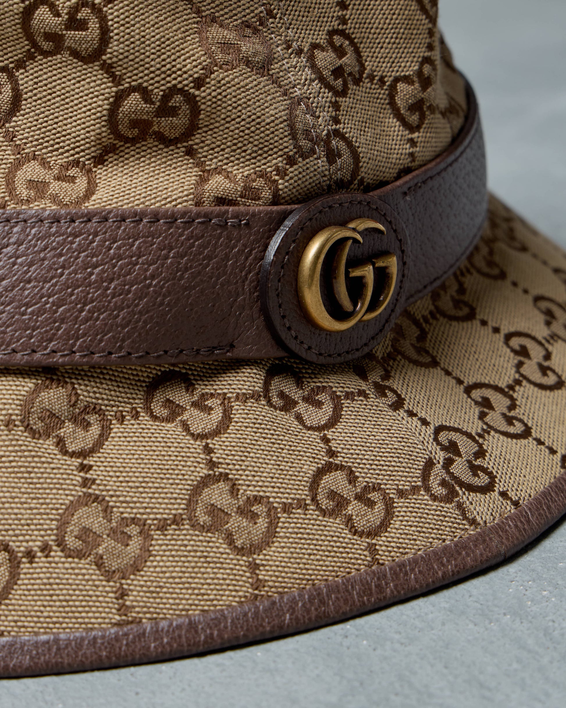 Close-up of a Gucci hat with patterned fabric and brown leather band.