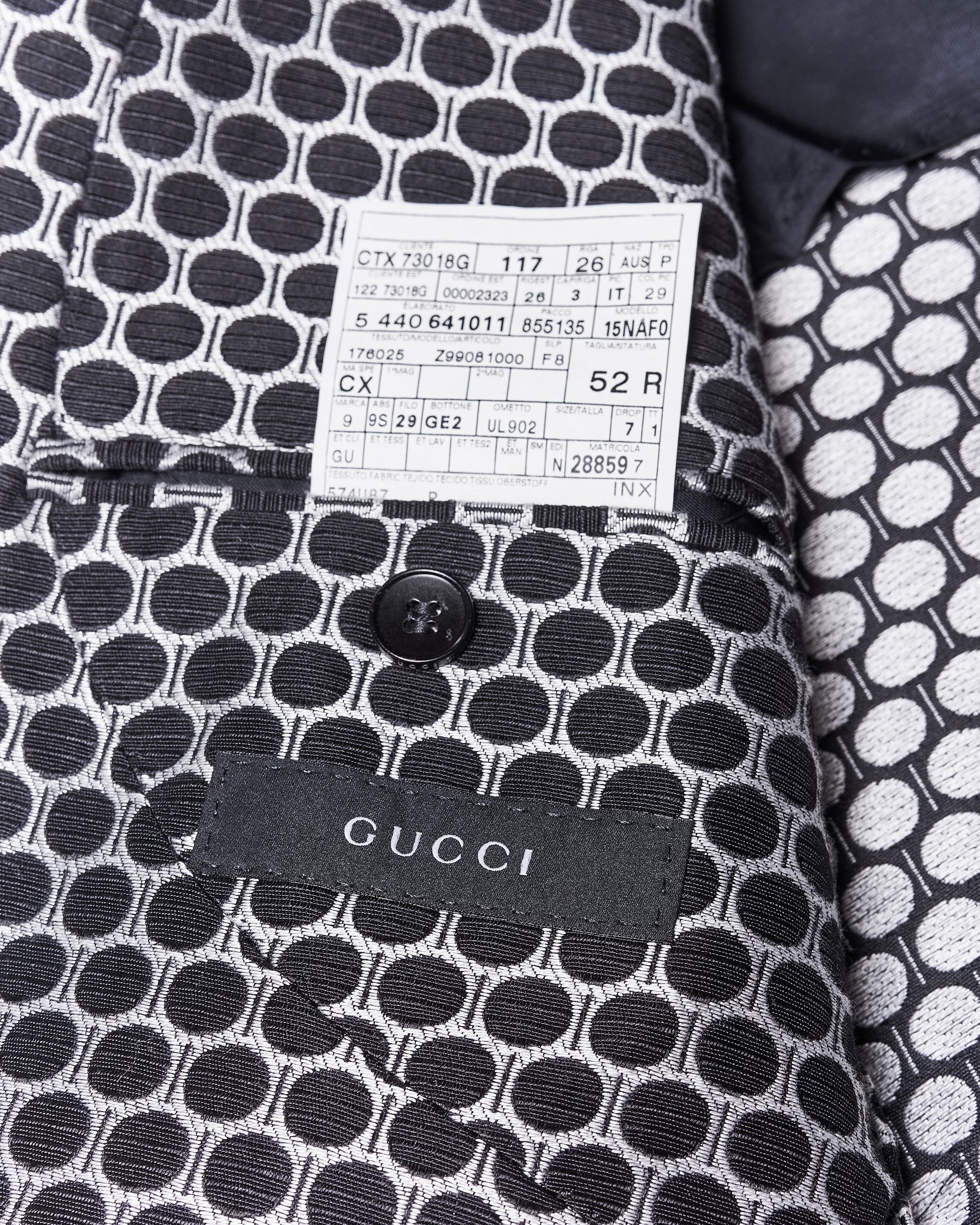 Close-up of a Gucci jacket's interior featuring a black and white circular pattern, a black button, and brand label.