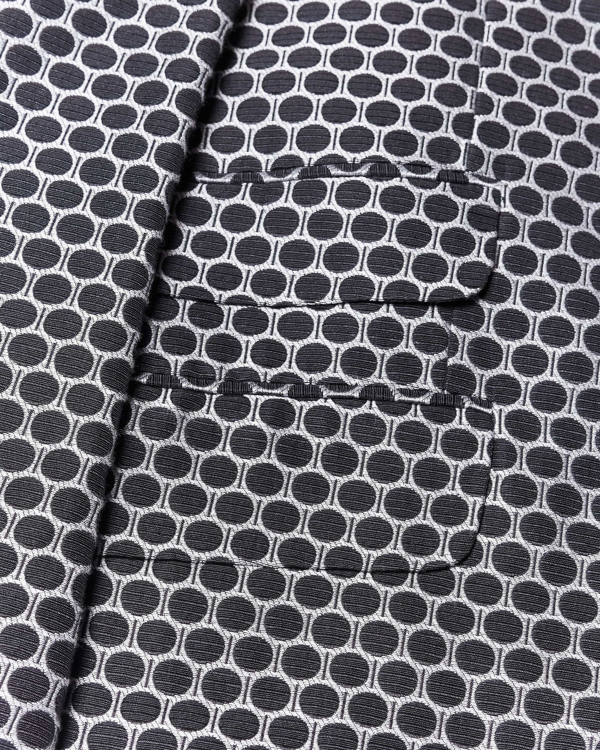 Close-up of a fabric with overlapping rectangular panels, featuring a circular black and white pattern from a Gucci by Tom Ford blazer.
