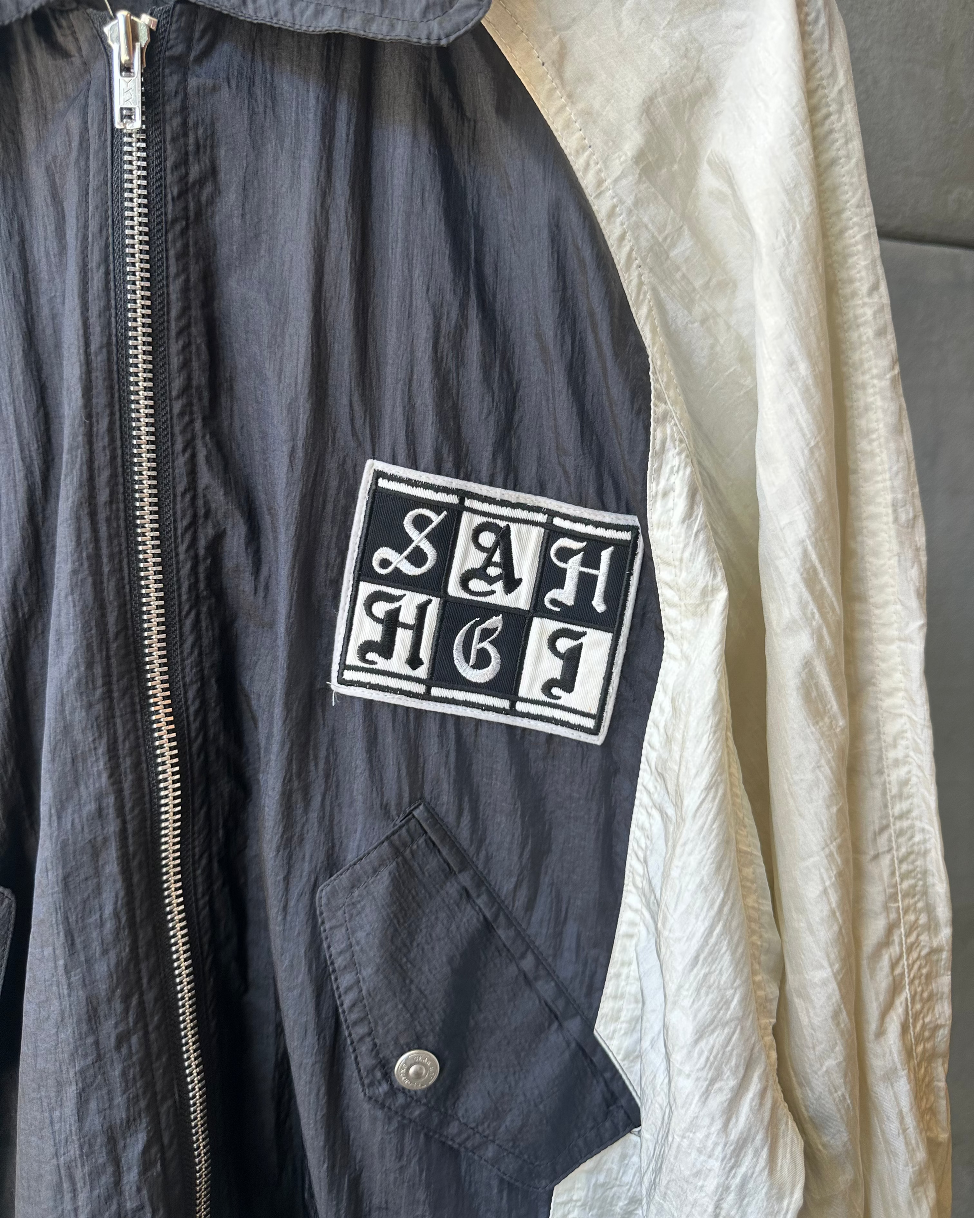 Black Hai Sporting Gear jacket with a logo patch on a gray background
